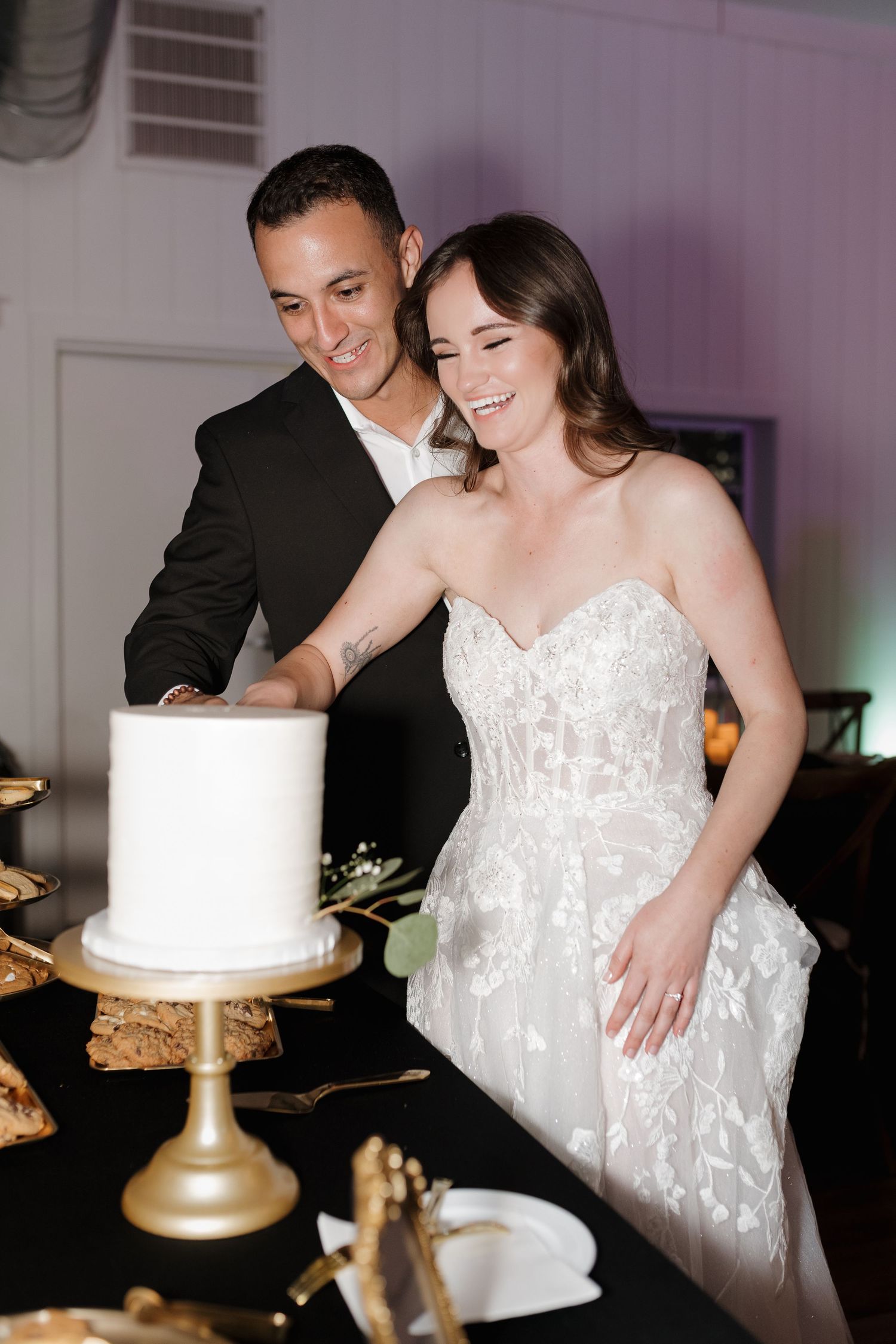 Couple shares sweet moment while cutting their elegant white wedding cake.