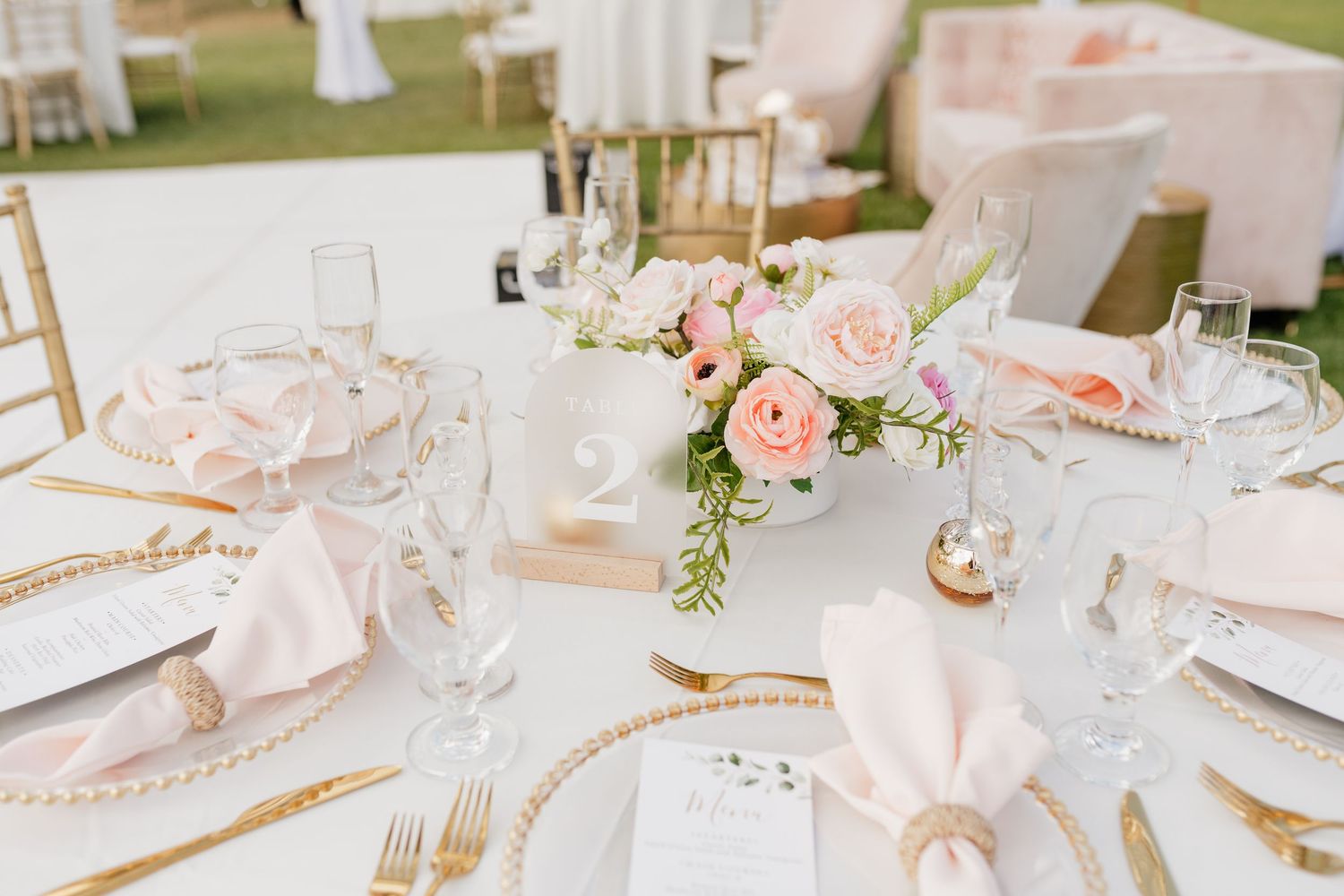 Close-up of romantic blush pink and white table decor with delicate place settings.