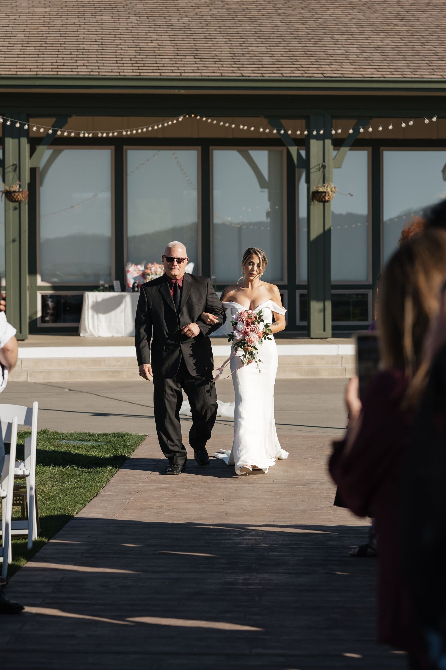 Wedding ceremony entrance with string lights and modern building architecture.