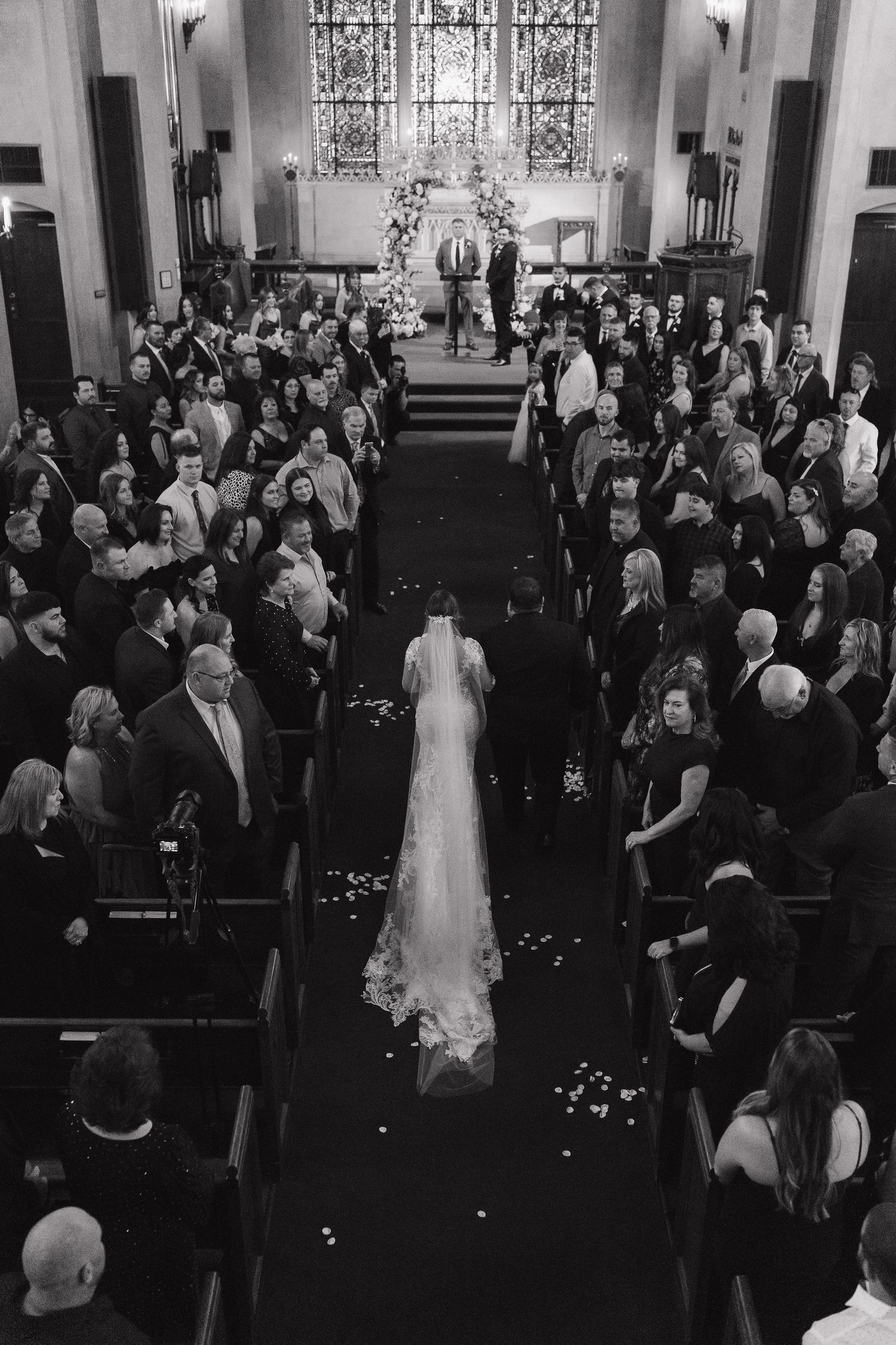 Wide view of traditional church wedding ceremony with guests seated in wooden pews.
