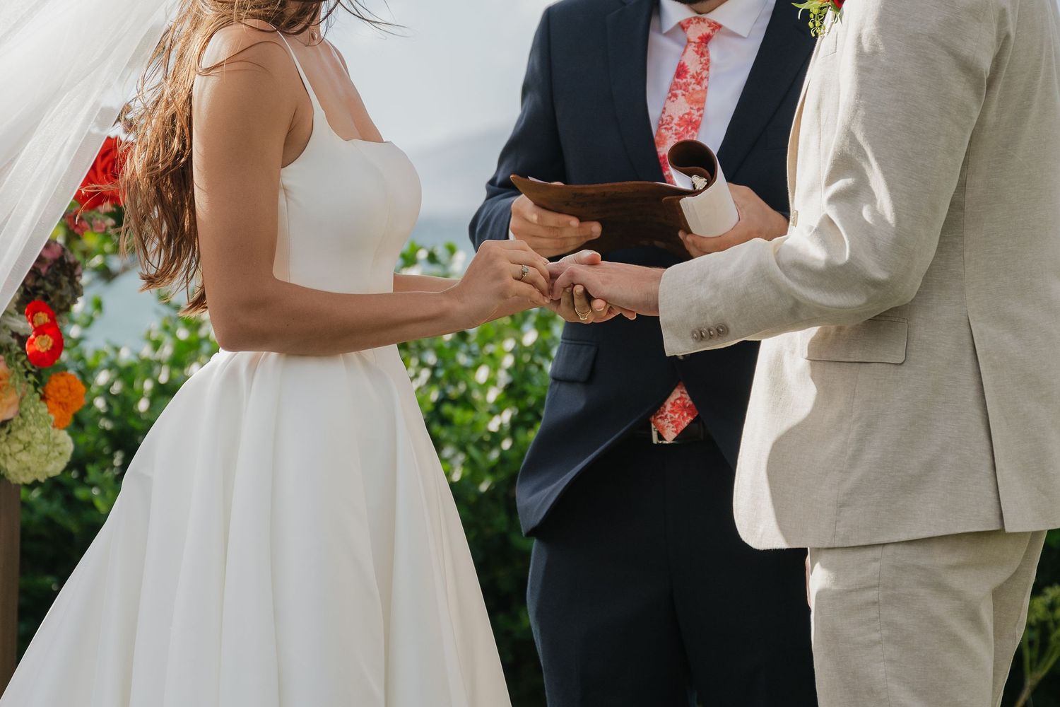 Wedding ceremony in progress with guests seated in wooden chairs on a grassy lawn overlooking scenic mountains.