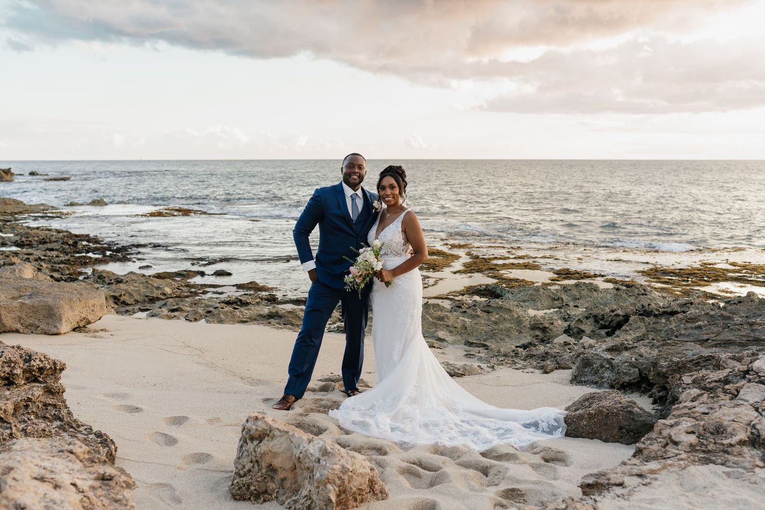 Wedding portraits captured along scenic rocky coastline at sunset.