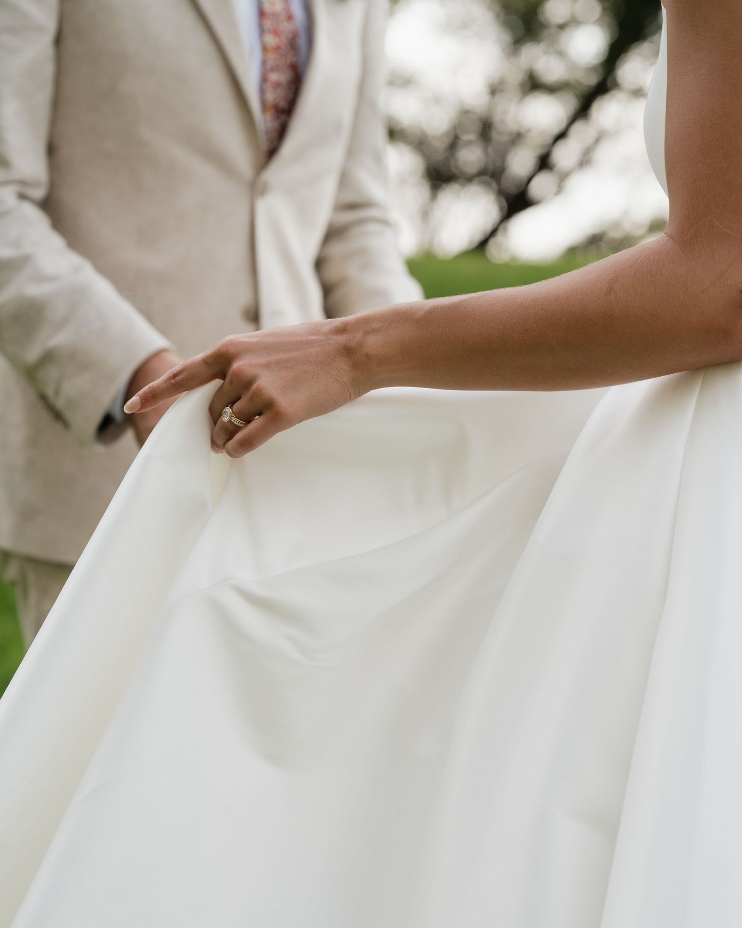 Close-up detail shot of white wedding dress fabric flowing in gentle motion.