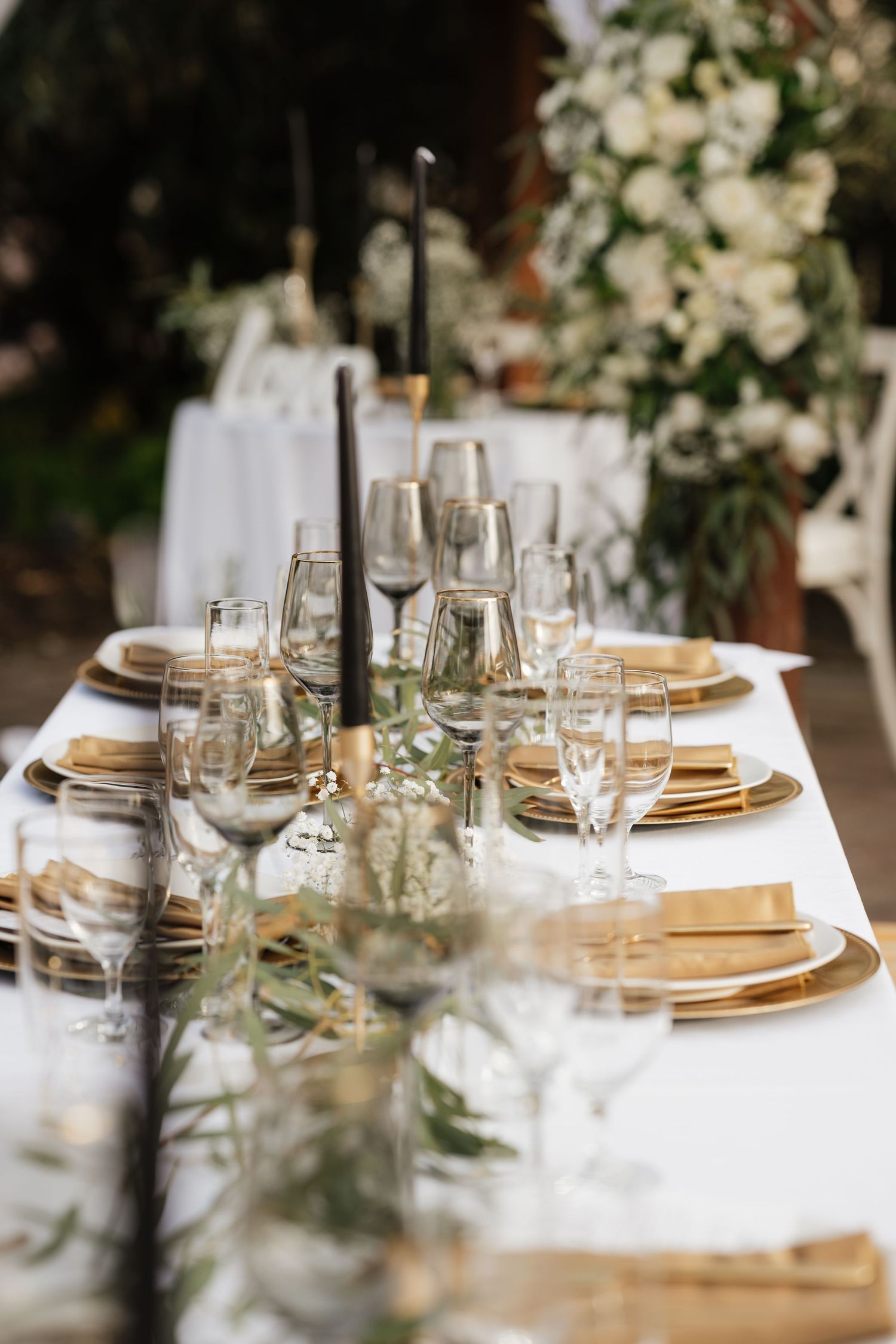 Formal table settings with gold chargers, crystal glasses, and white table linens.