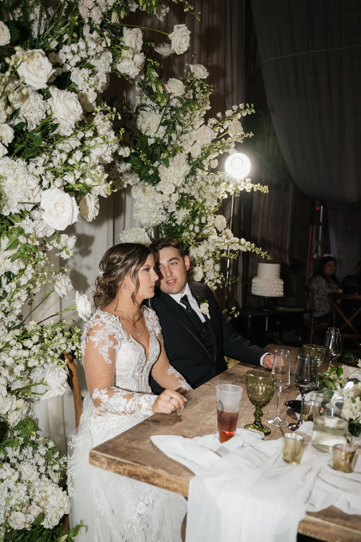 Elegant wedding reception setup with white floral arch and rustic table decor.