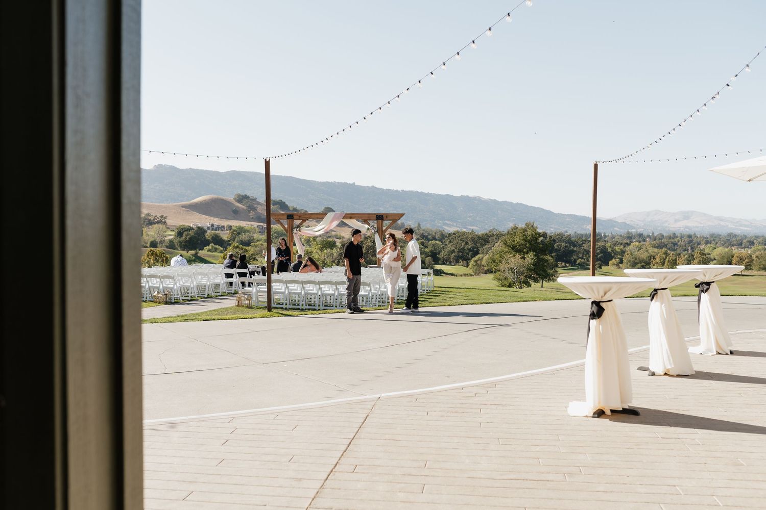 Outdoor wedding venue with string lights against mountain landscape.