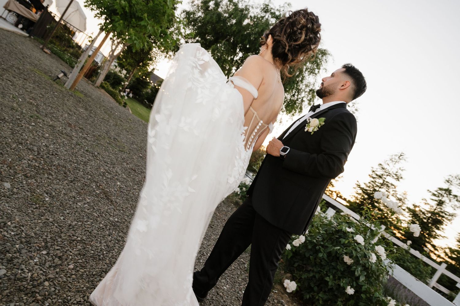 Outdoor wedding portraits with scenic garden backdrop and string lights.