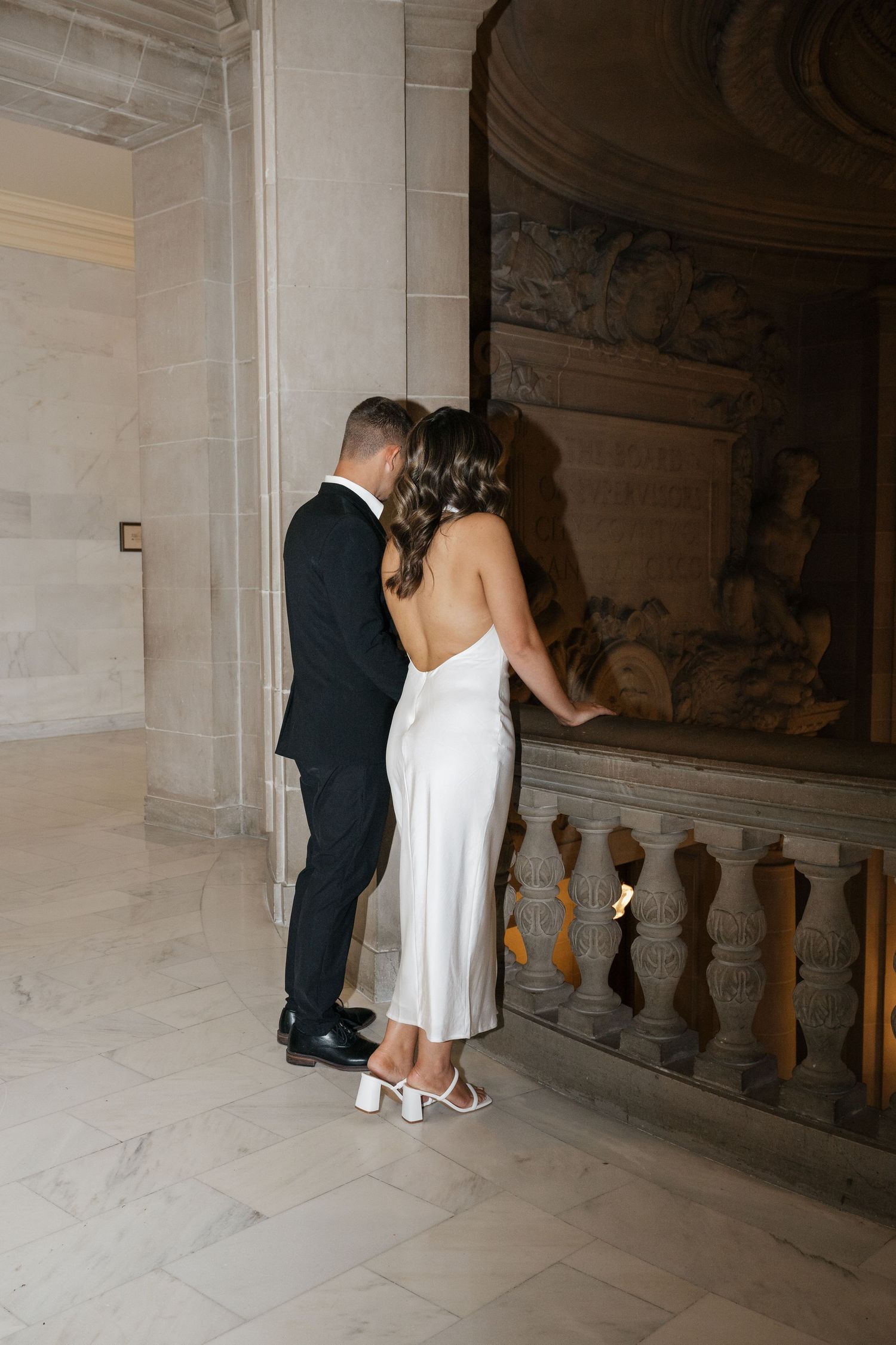 Intimate moment in an elegant marble hallway with ornate architectural details.
