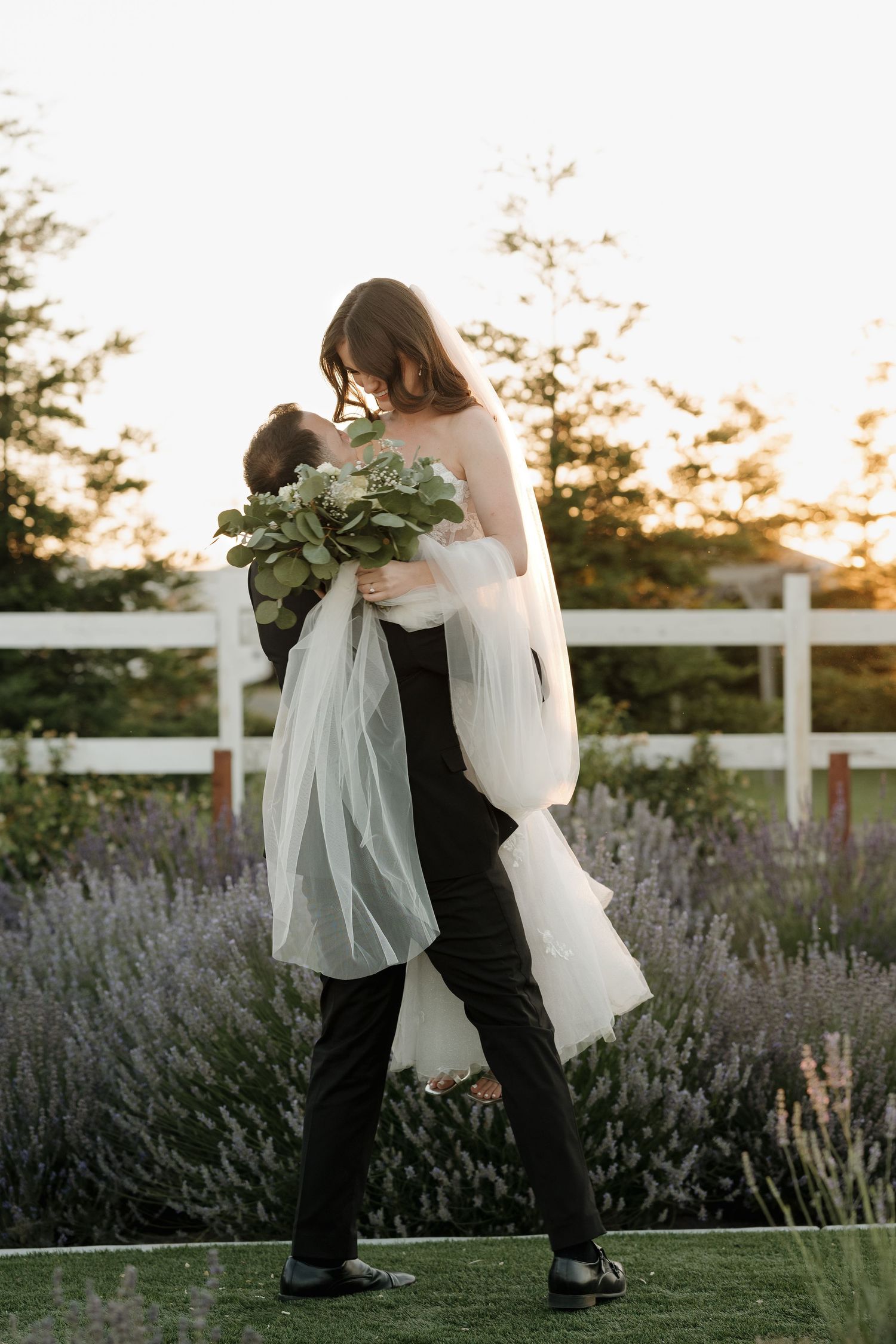 Romantic moment between couple among blooming lavender plants during golden hour.