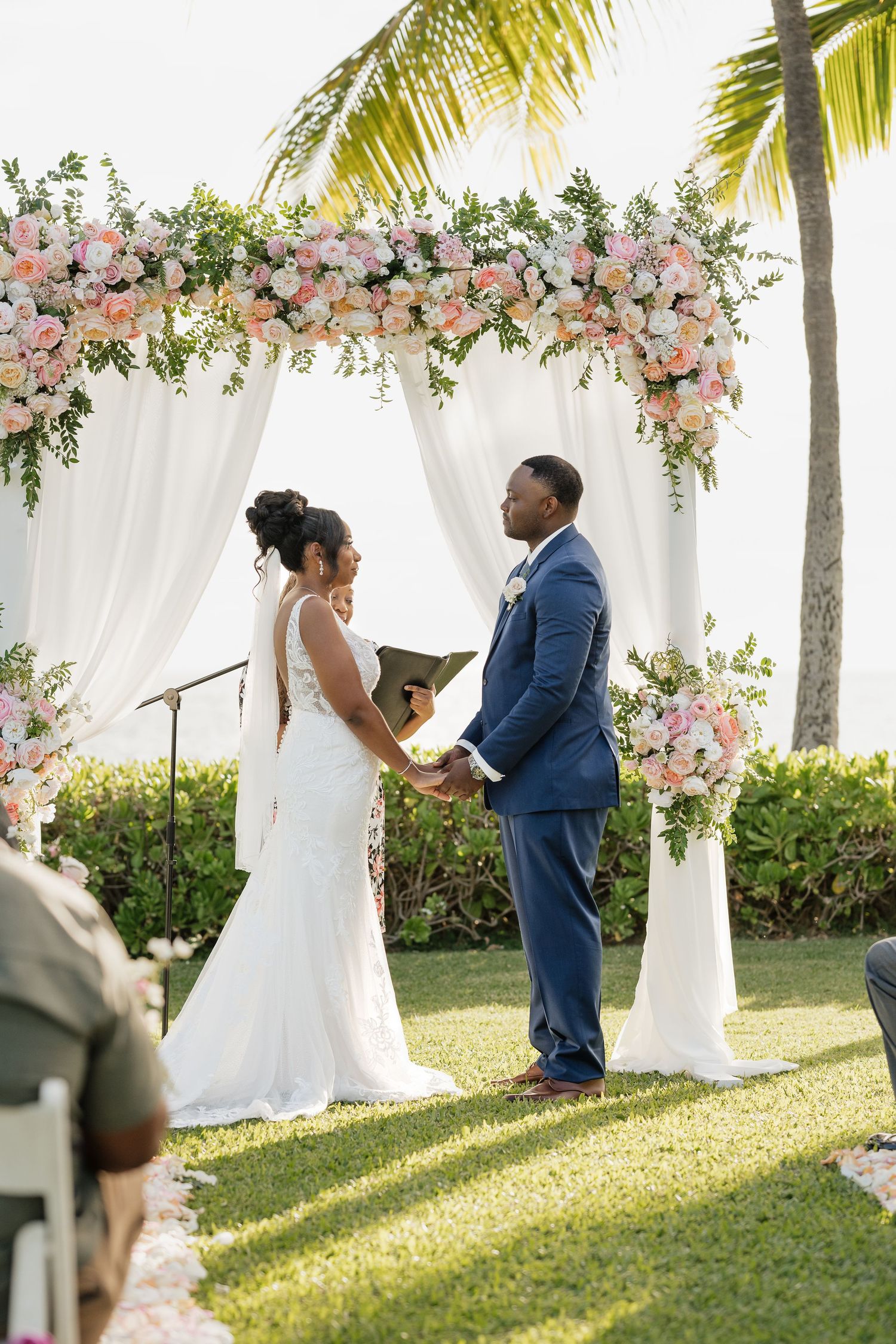 Romantic outdoor ceremony under white canopy decorated with pink floral arrangements.