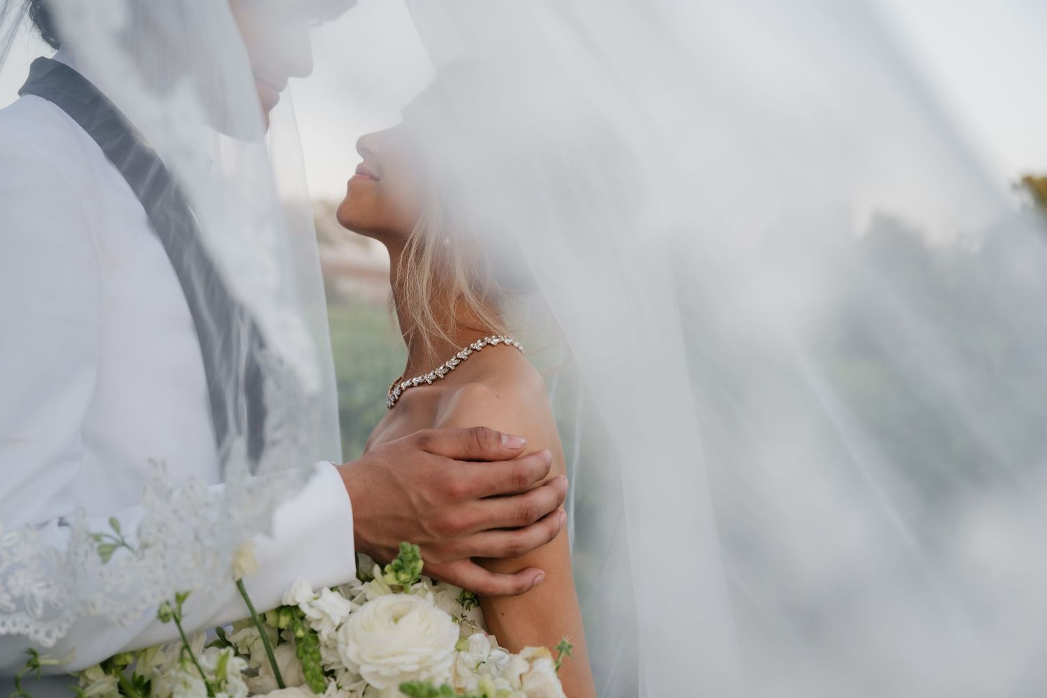 Elegant close-up of hands holding a white rose bouquet during a wedding ceremony.