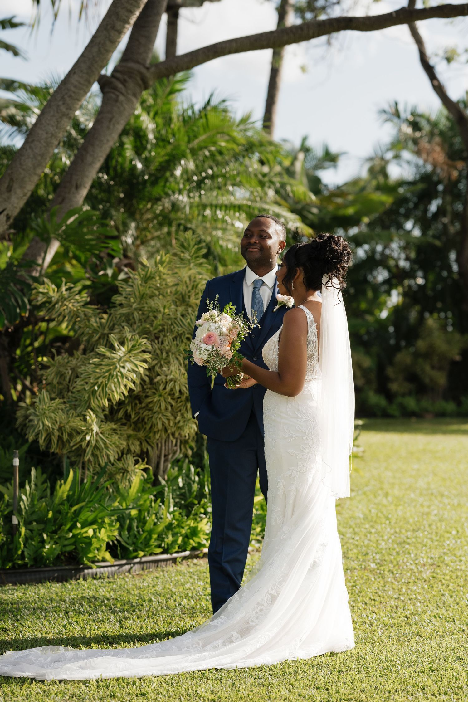 A wedding moment captured in a tropical garden setting with palm trees and greenery.