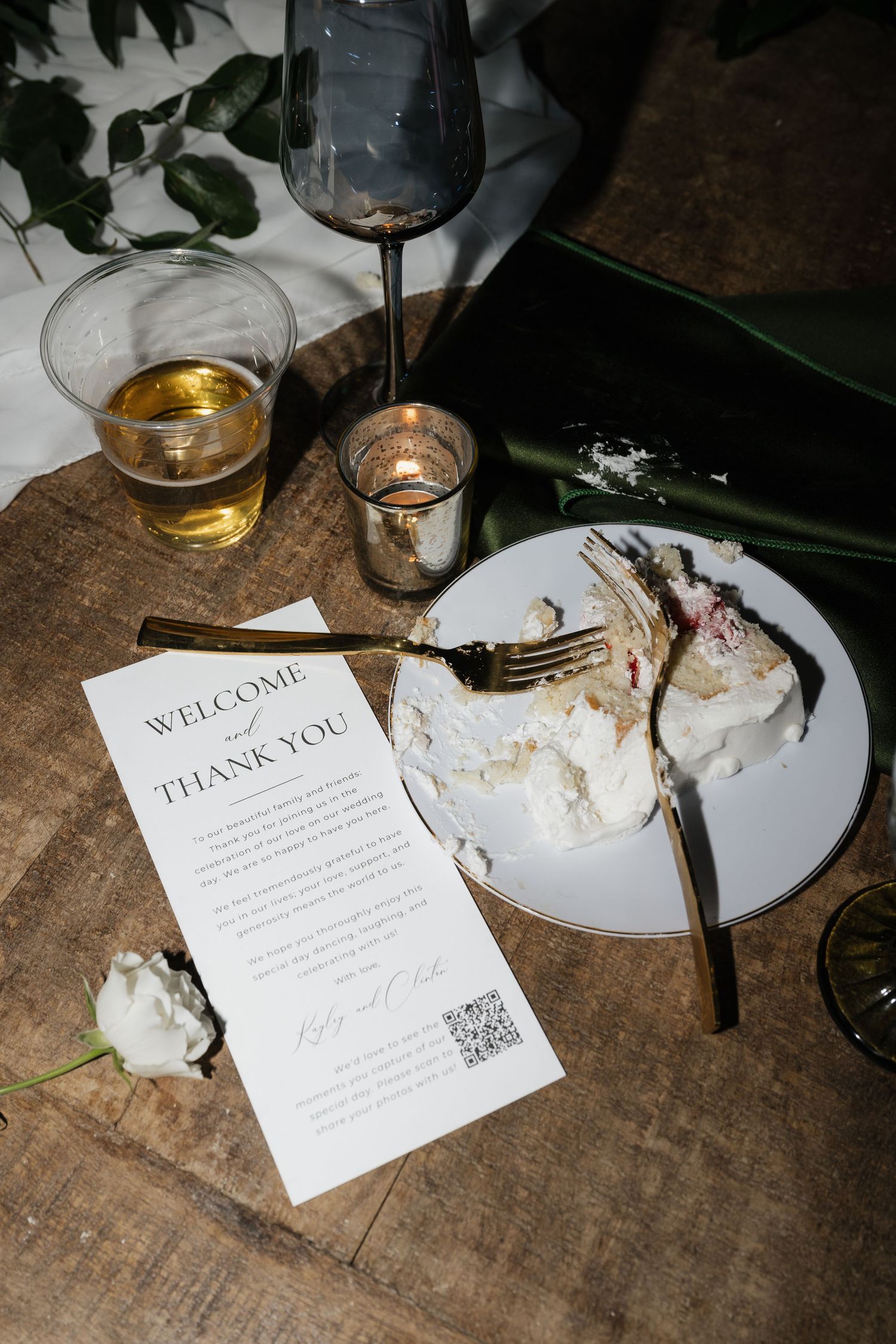 Wedding reception details with place cards and table settings on wooden surface.