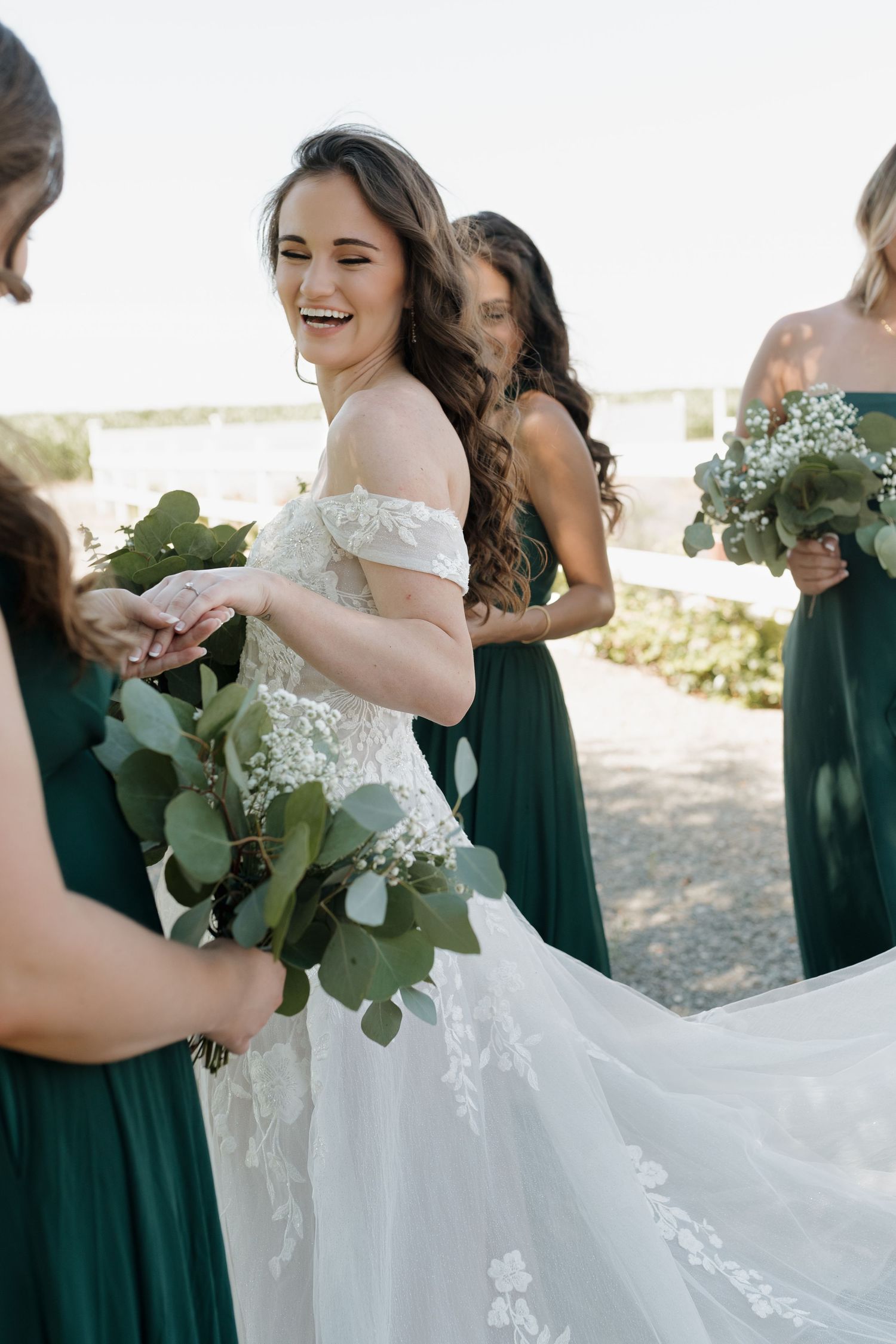 Wedding party in emerald and white dresses share joyful moments outdoors.