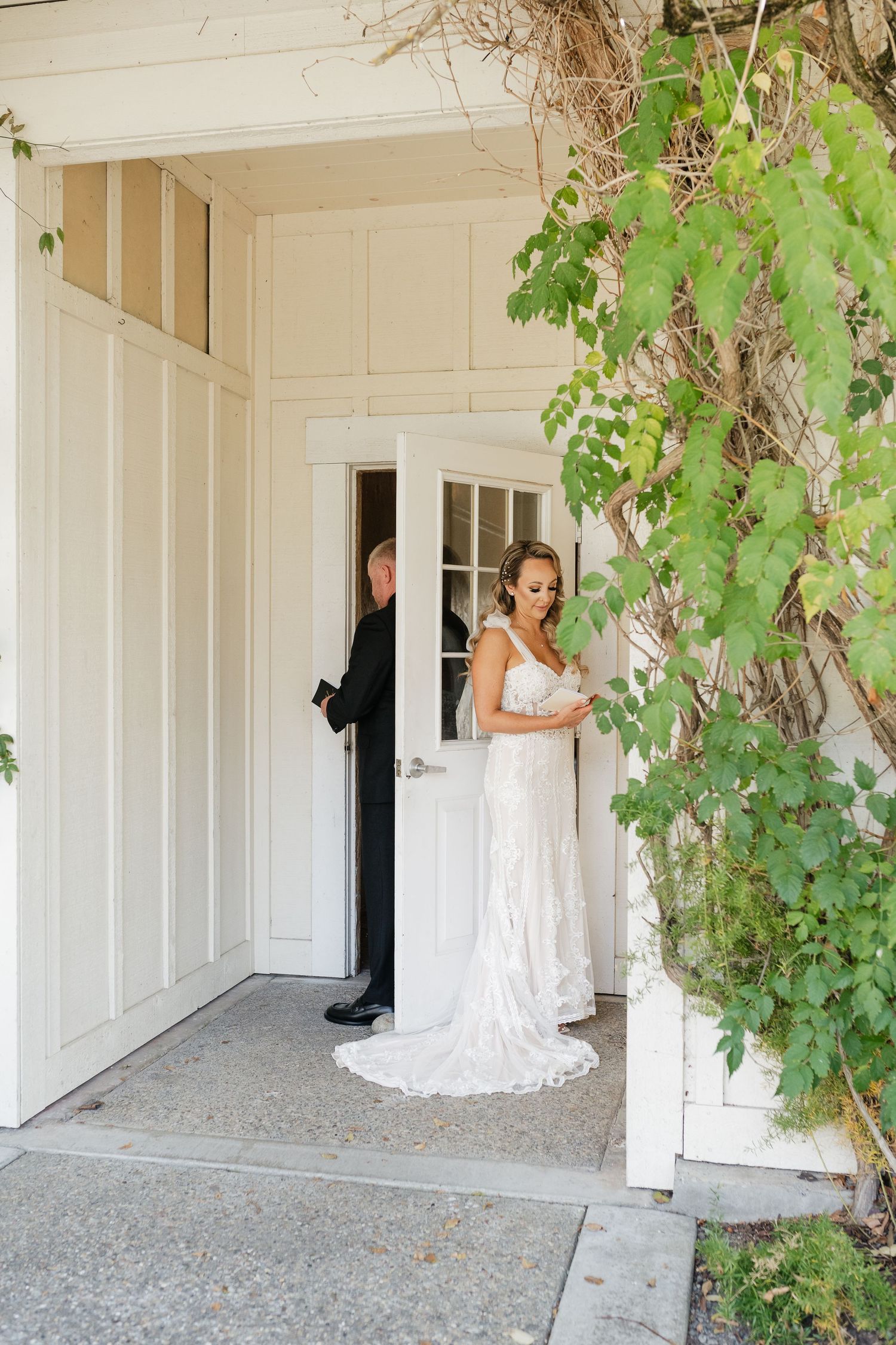 White wedding venue exterior with vine-covered pillars and covered entrance.
