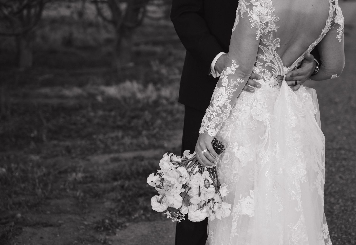 A couple embraces in formal wedding attire, captured in black and white photography.