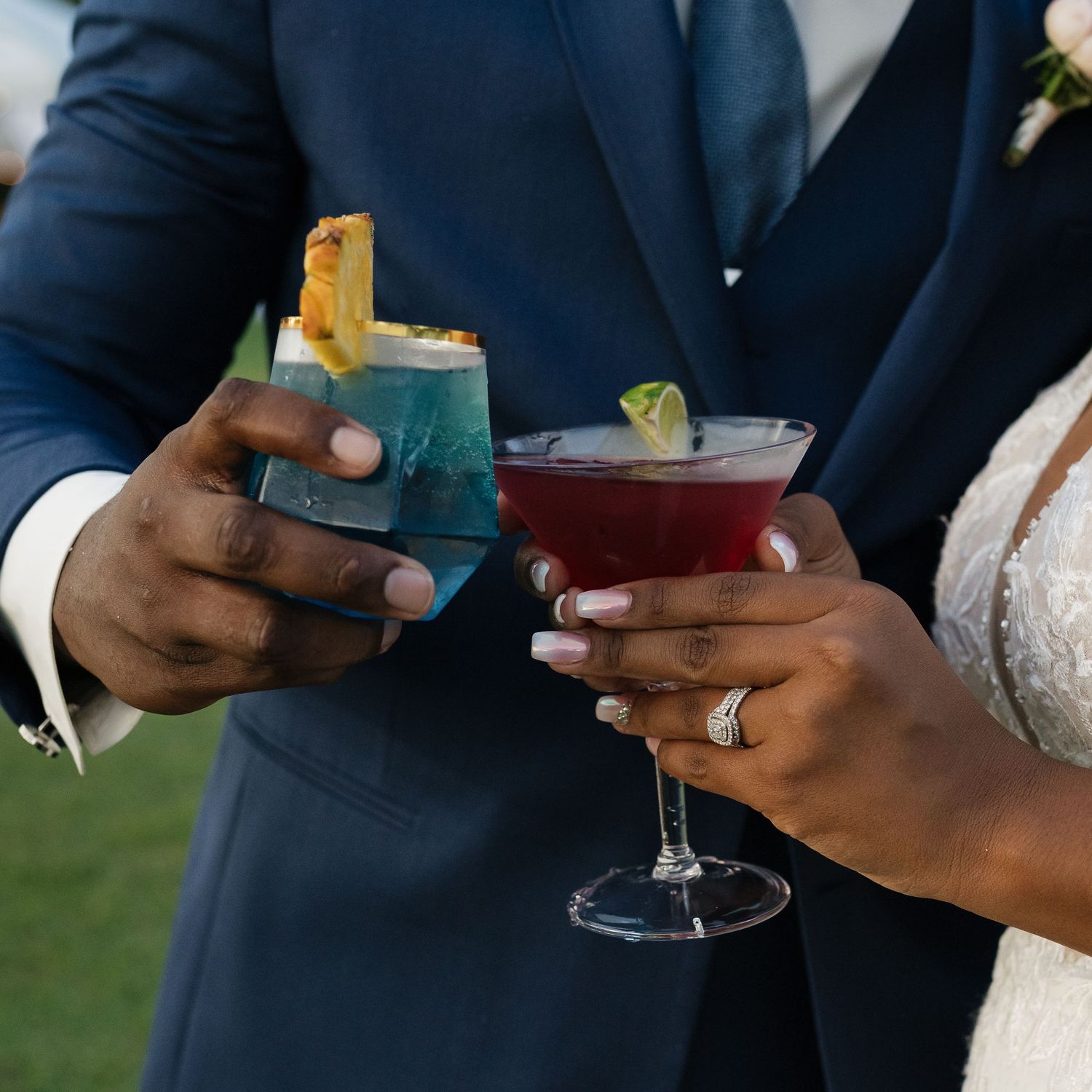 Guests in formal attire holding cocktails during an outdoor wedding reception.