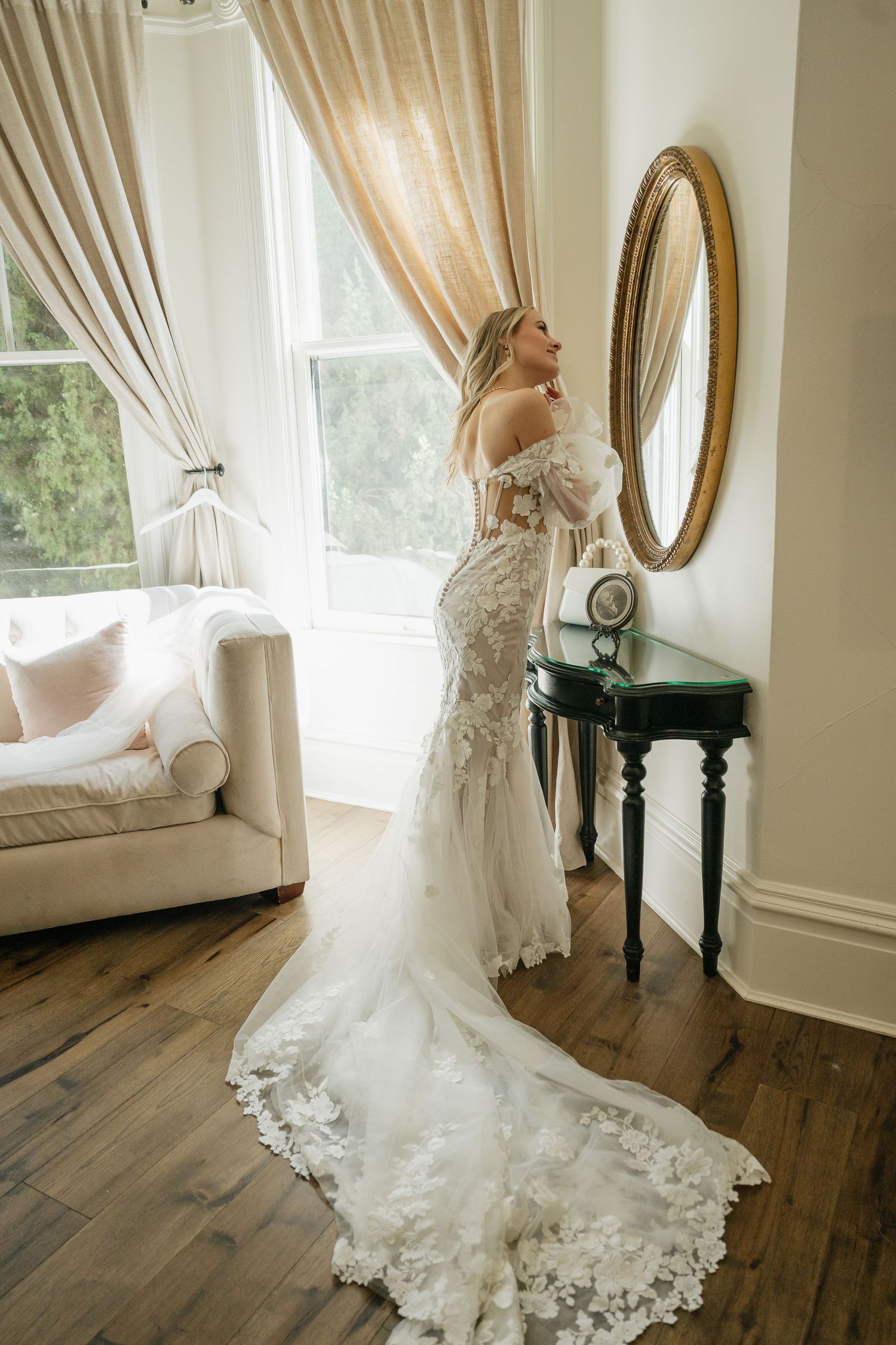 Bridal portraits in a sunlit room showcasing intricate lace wedding dress and long train.