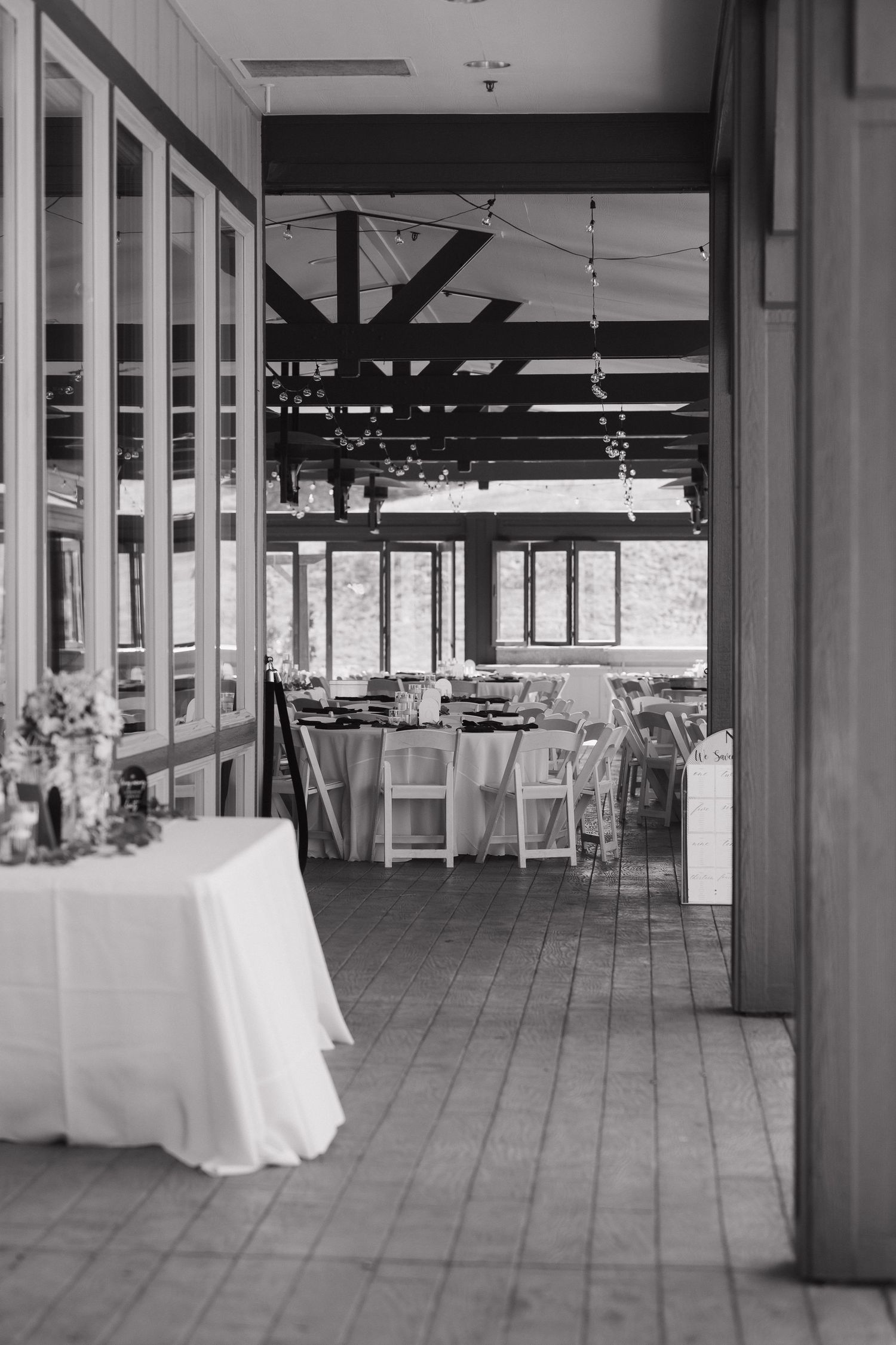 Modern indoor wedding venue with white pillars and large windows in black and white.