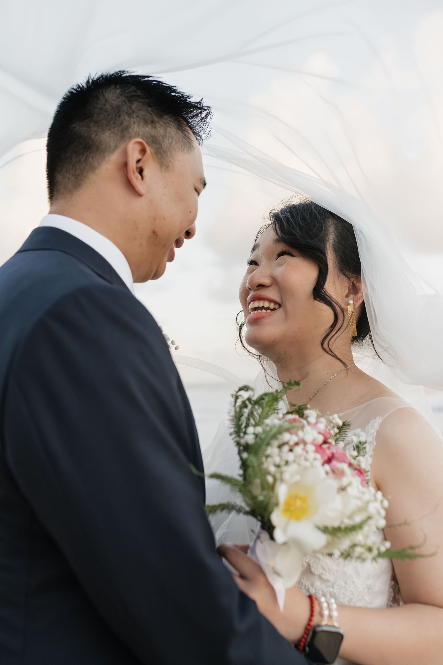 A couple sharing an intimate moment under flowing white veil during their wedding.