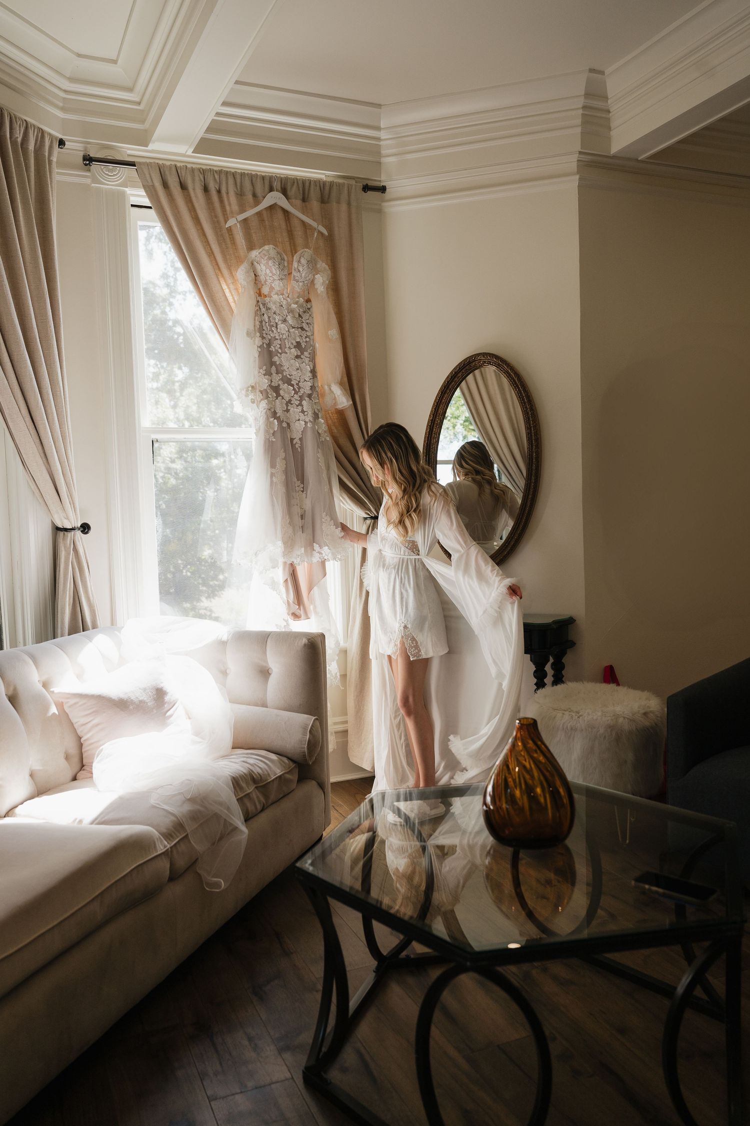 Ethereal white curtains billow in breeze by window with antique furniture creating dreamy atmosphere in sunlit room.