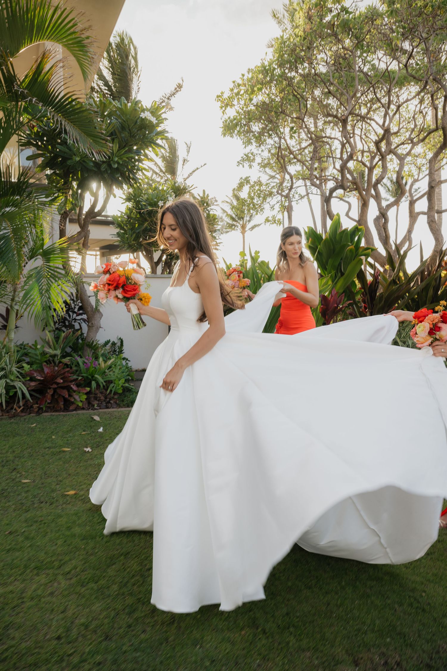 A bride's white wedding dress flows beautifully in the tropical garden setting with palm trees.