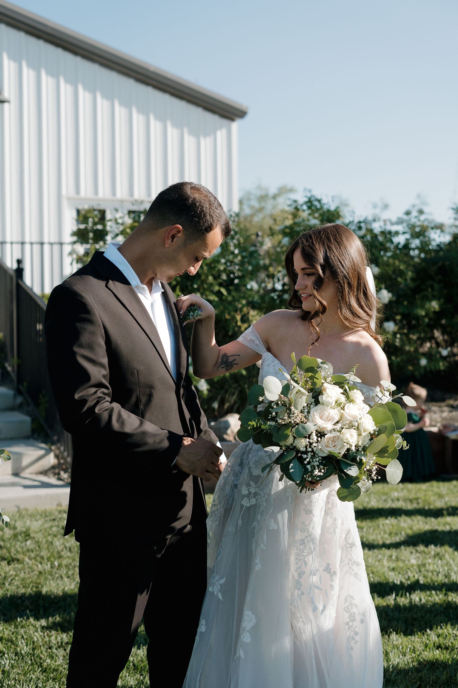 Couple shares intimate moments during outdoor wedding photoshoot with white building backdrop.