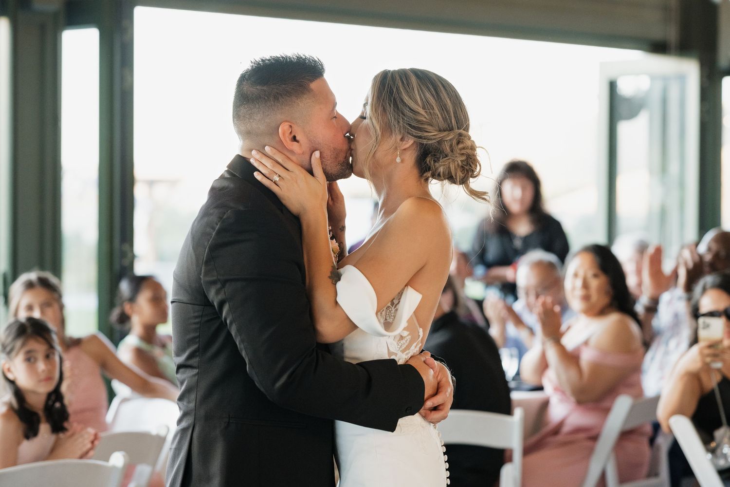 Elegant indoor wedding reception features first dance with guests watching.