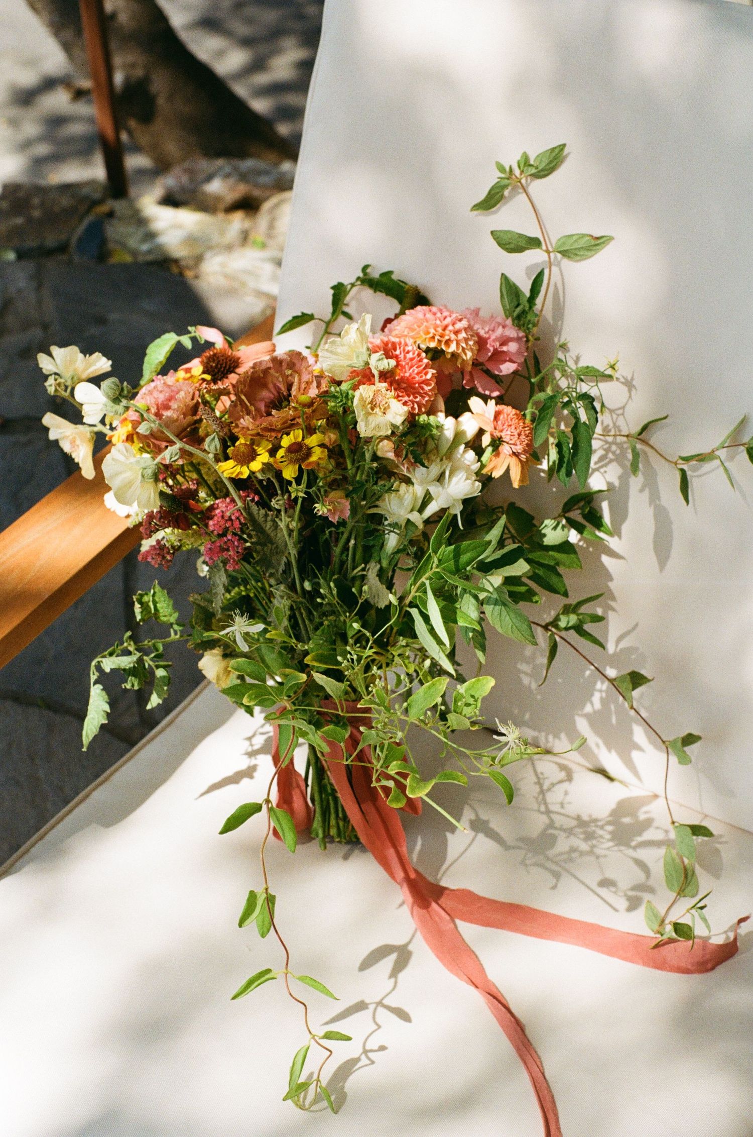 A series of five elegant floral arrangements with coral and white blooms tied with peach ribbons cast gentle shadows.