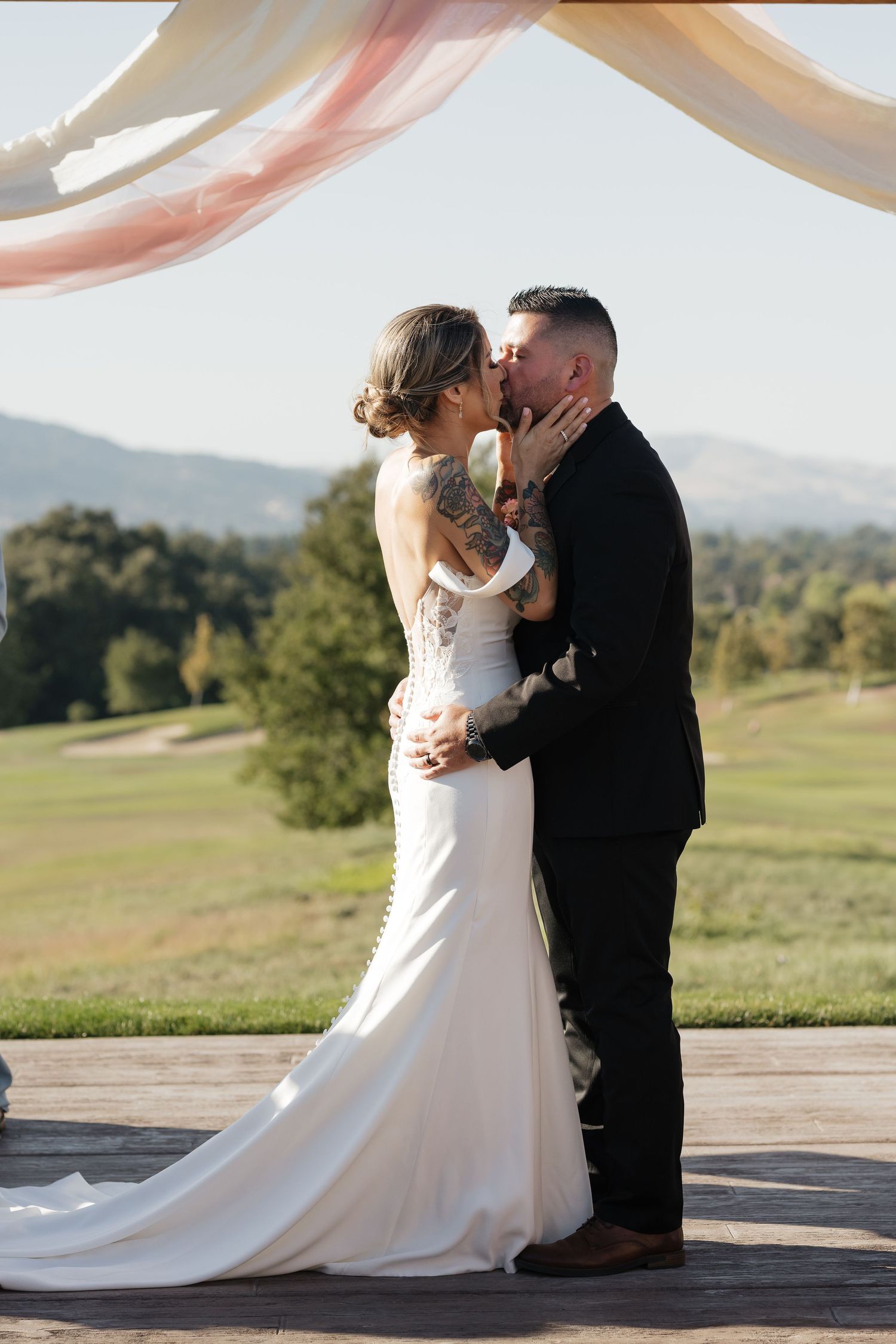 Intimate wedding moment shared under pink drapery with scenic mountain backdrop.