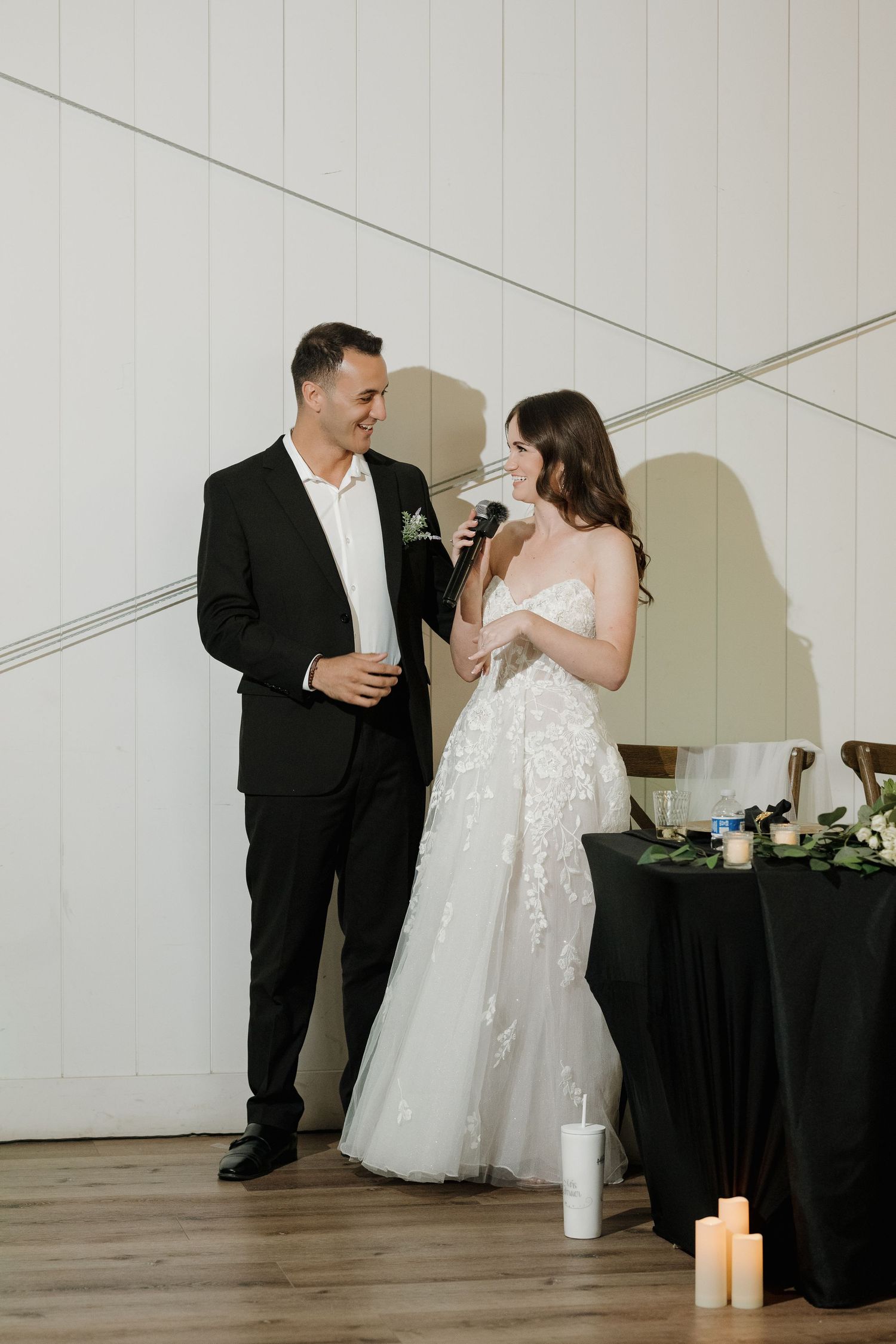 Couple shares intimate dance moments in minimalist white reception venue with black decor accents.