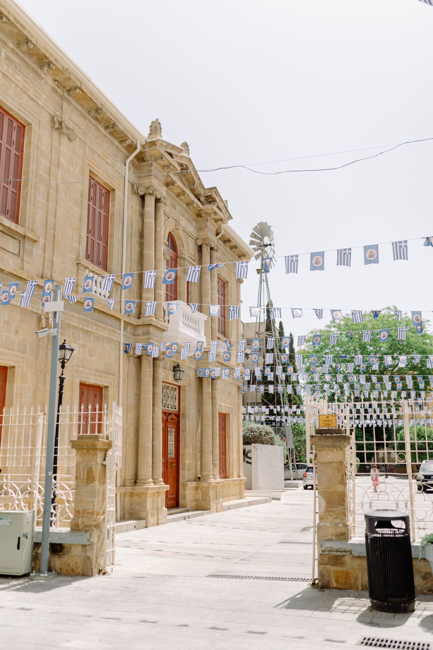 Historic limestone building with decorative bunting flags strung across a sunny courtyard entrance in Malta.