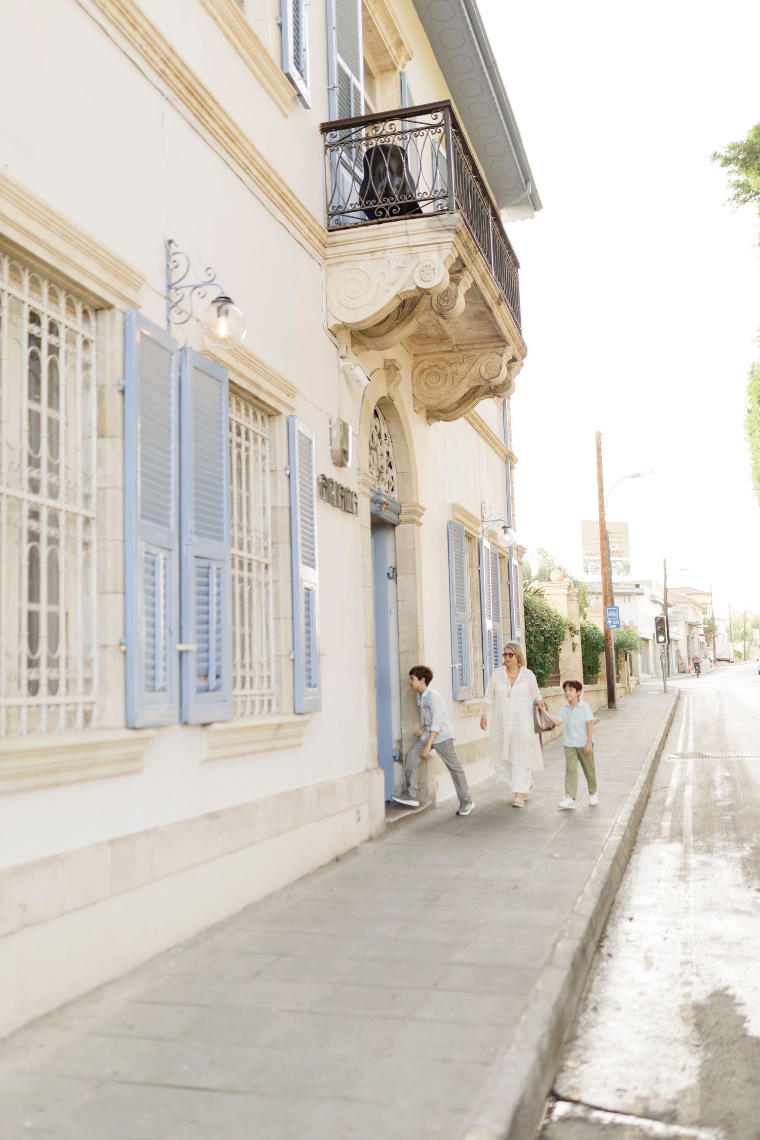 Family walking along a charming European street with blue shuttered windows and ornate building facade.