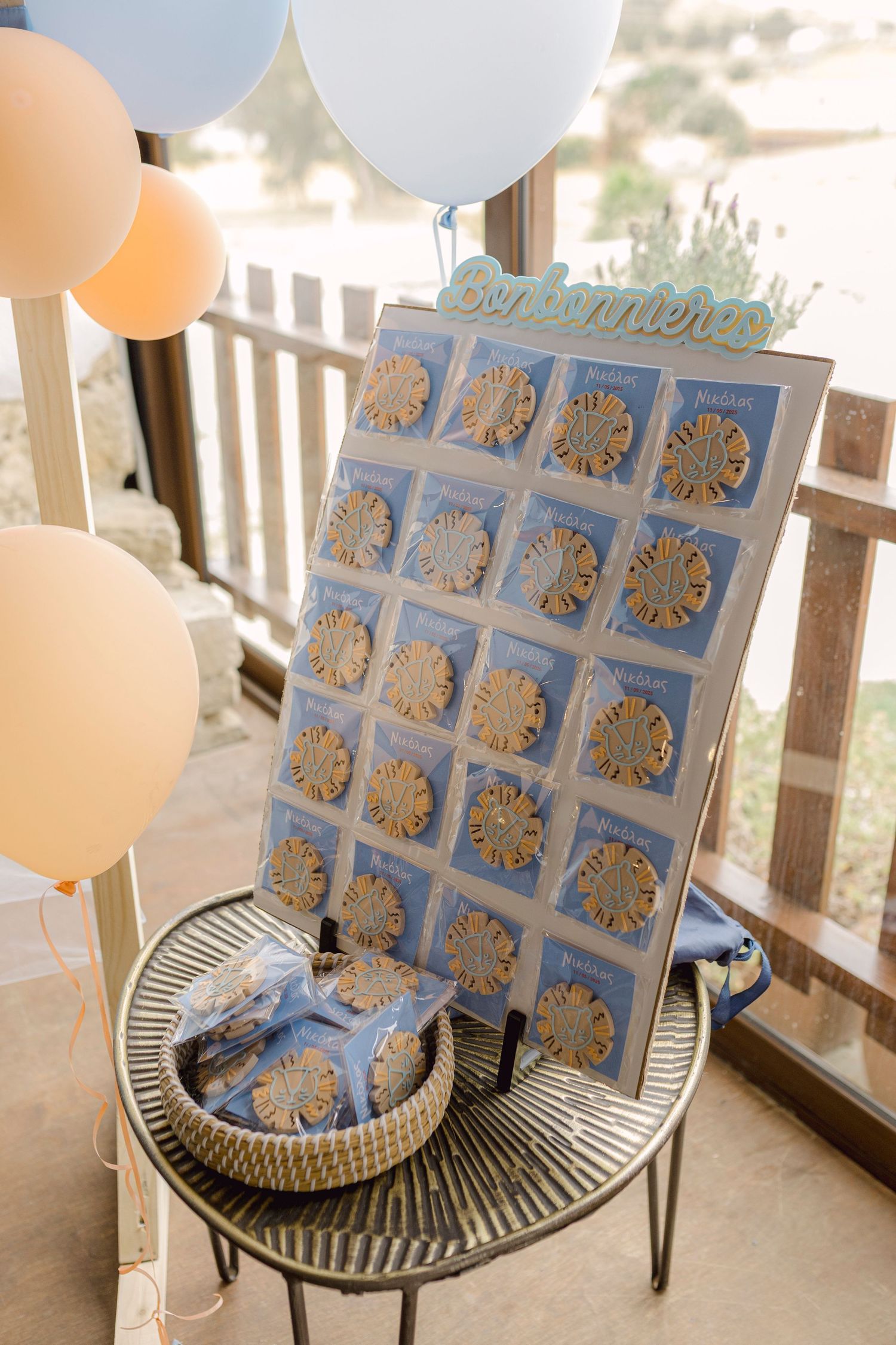Blue and peach balloon-decorated baby shower favor display board on a metal table.