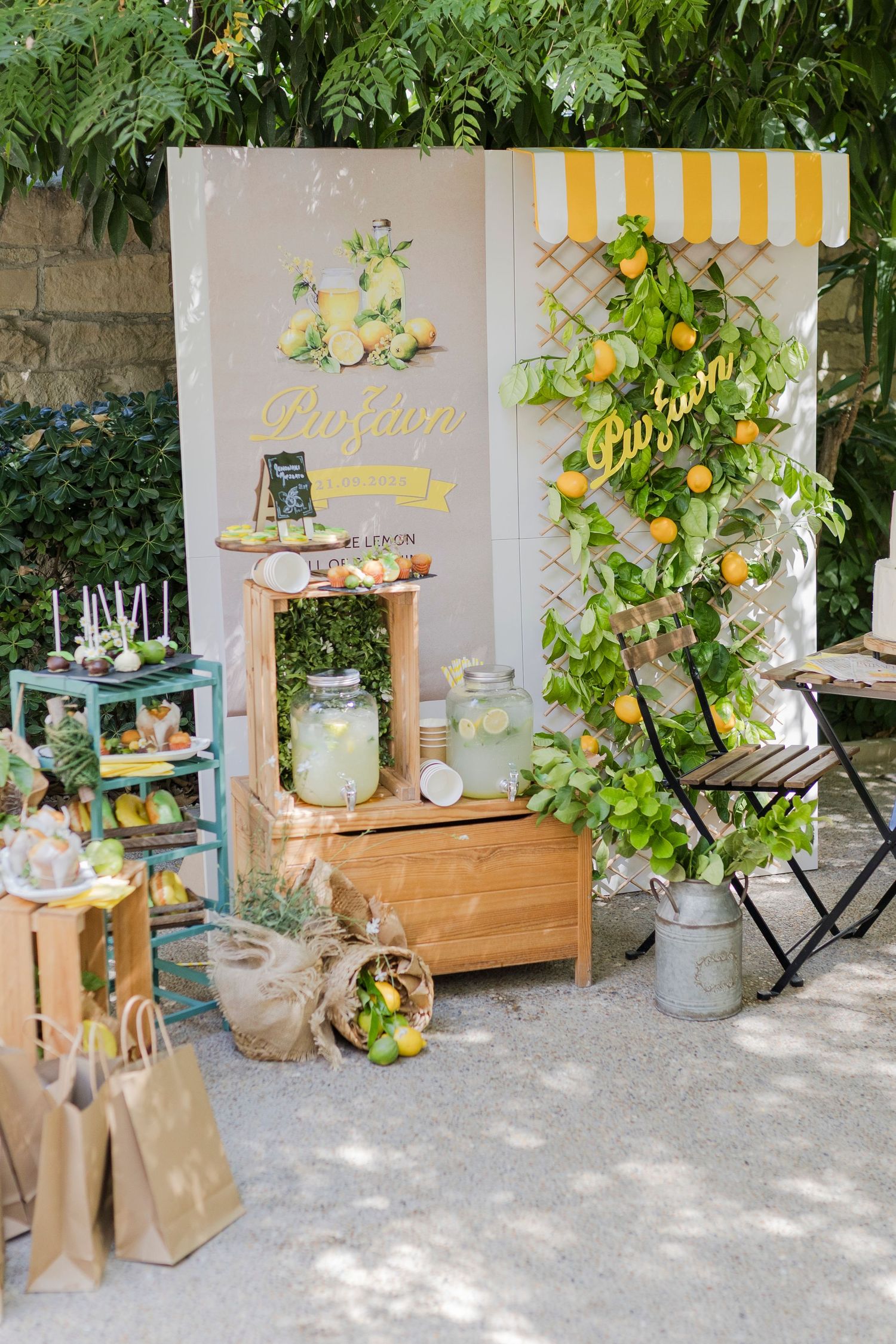 Charming lemon-themed outdoor party setup with yellow striped awning, lemonade dispensers, wooden crates, and citrus decorations.