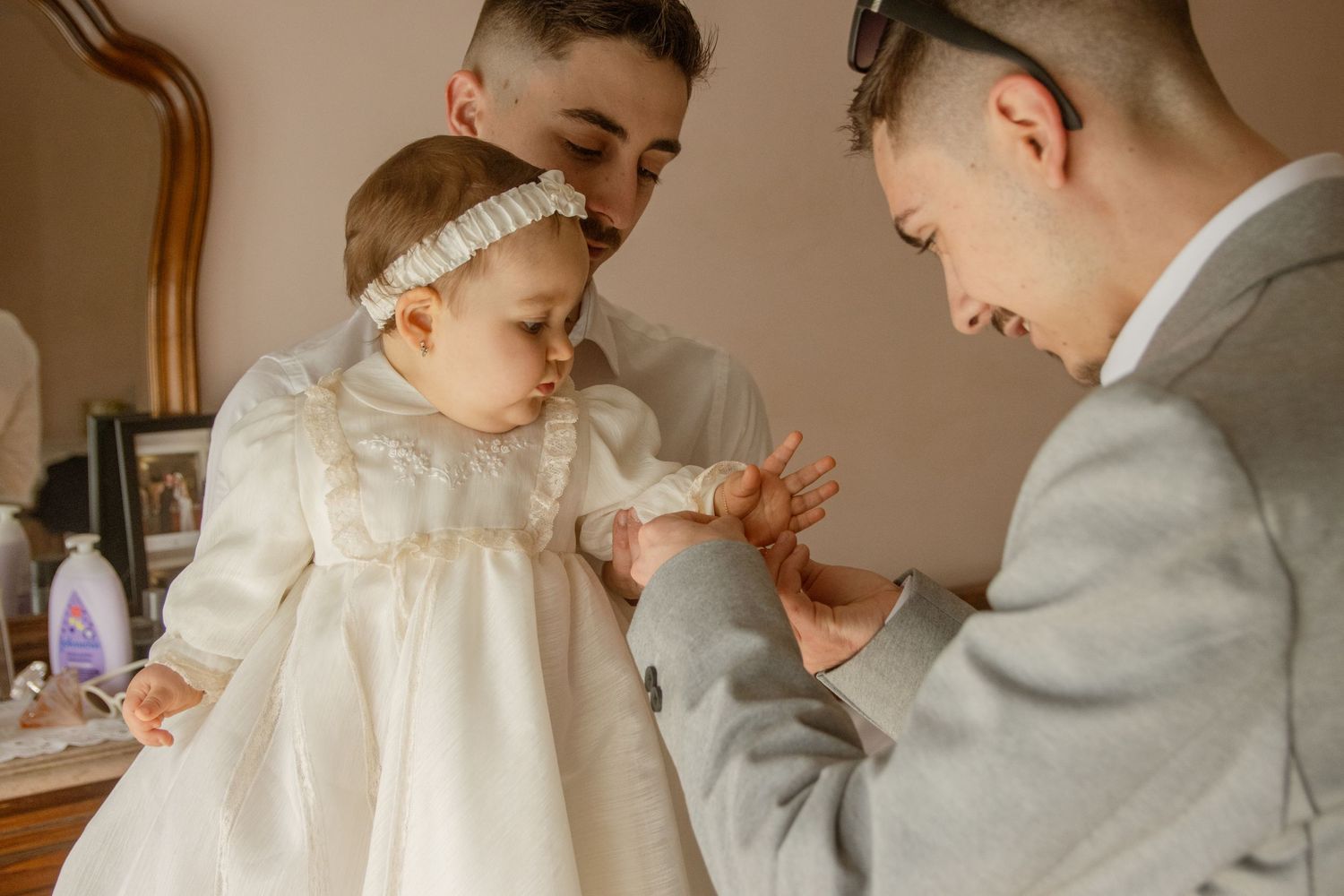 Fotografia de batizado. Bebé com o pai e o padrinho em casa. Póvoa de Varzim