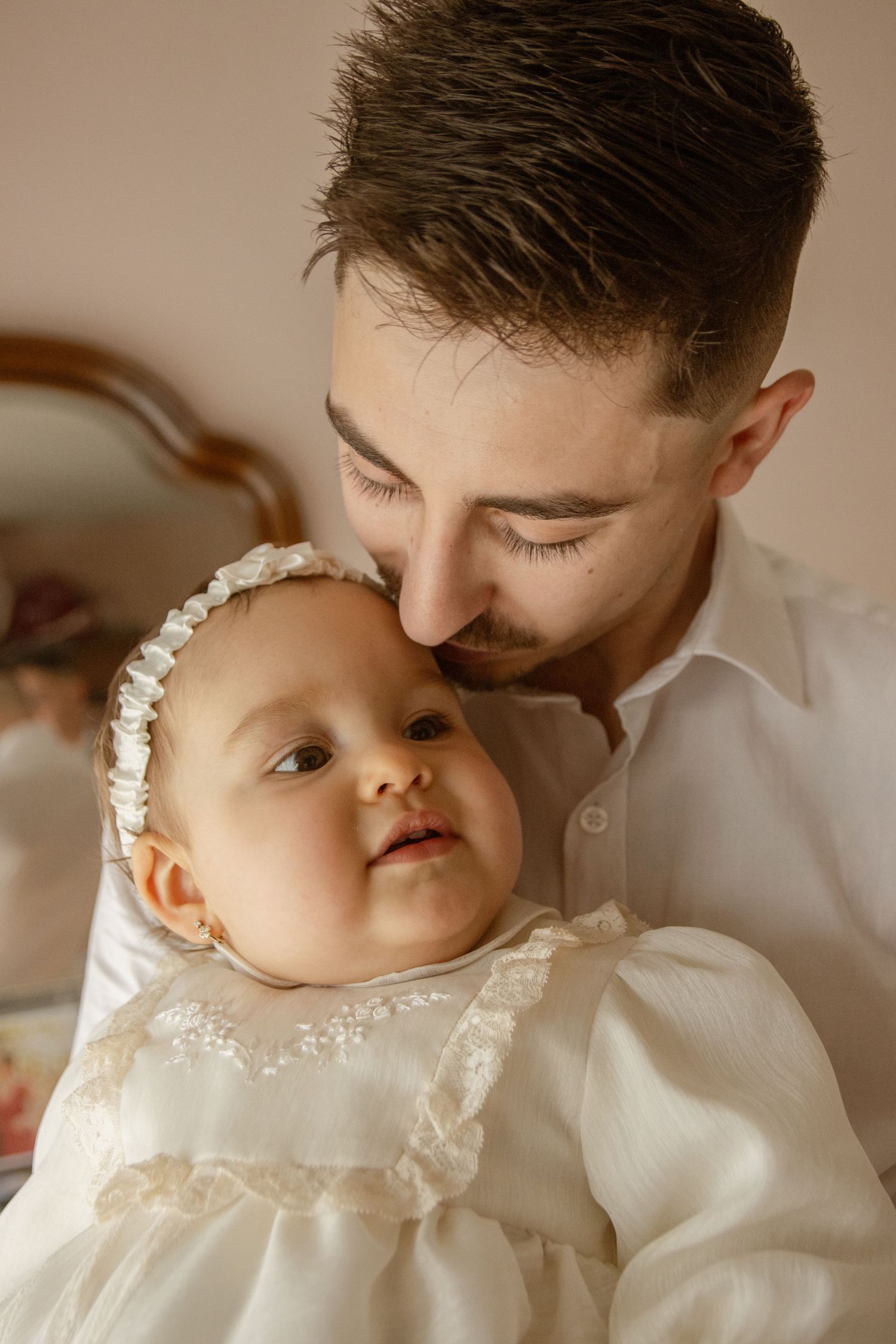 Fotografia de batizado com bebé no colo do pai, em casa. Póvoa de Varzim