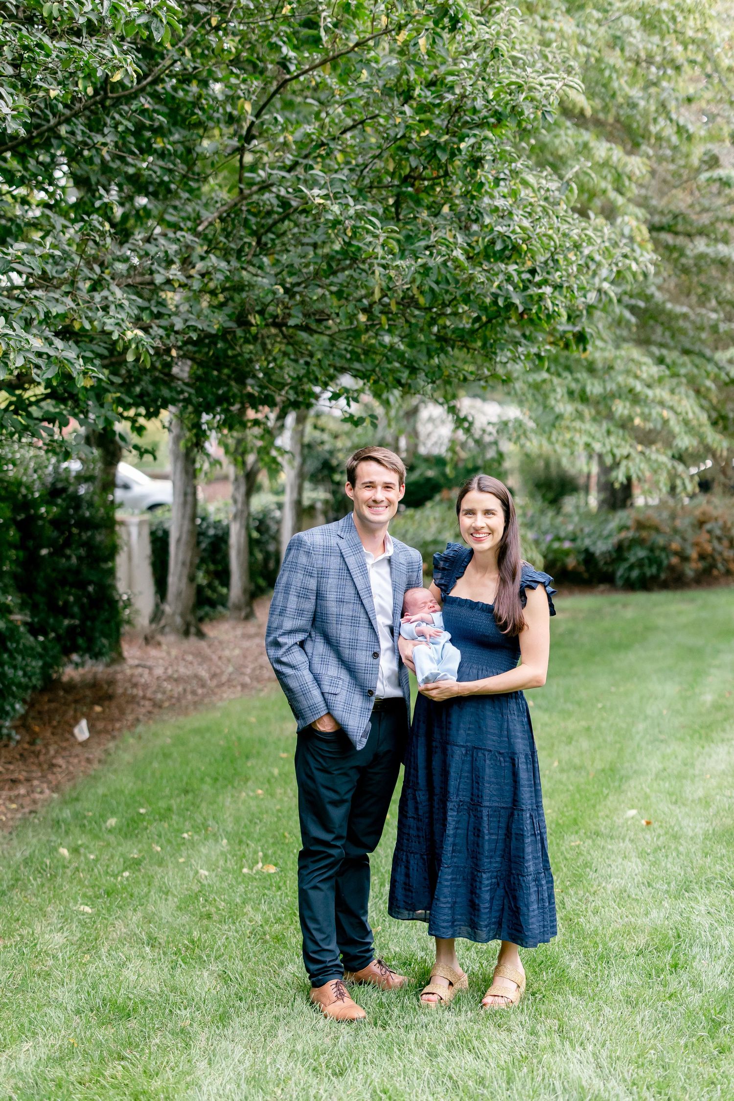 Two people share a romantic moment in a lush garden setting wearing blue and gray outfits.