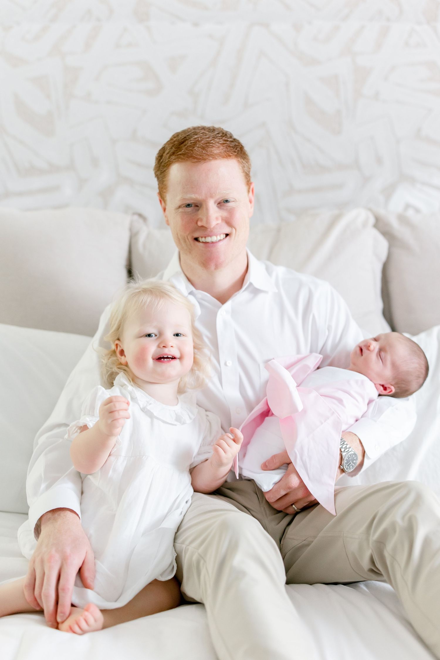 A family portrait on a white couch showing three people in bright, coordinated outfits.
