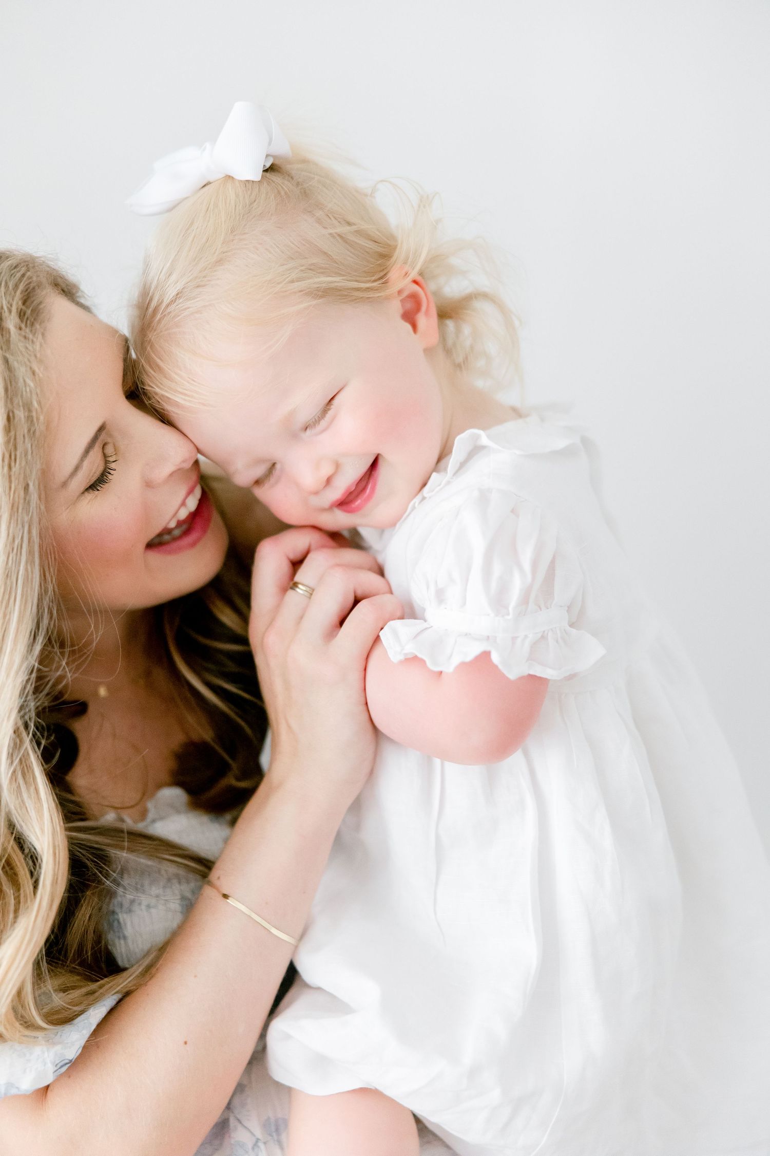 A sweet candid moment between two people sharing laughter against a white background.