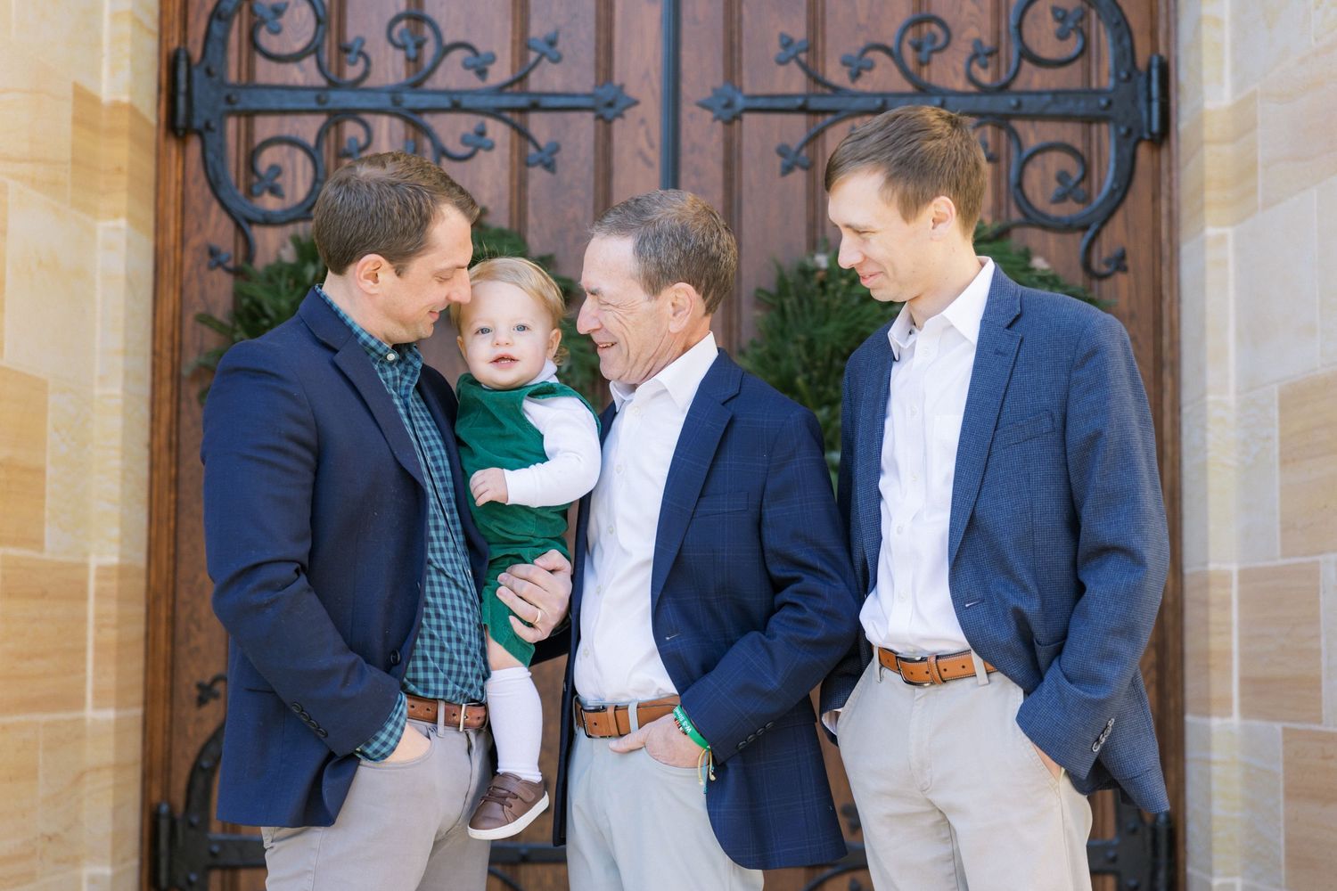Family group wearing coordinated navy and white outfits pose together outside ornate wrought iron church doors.