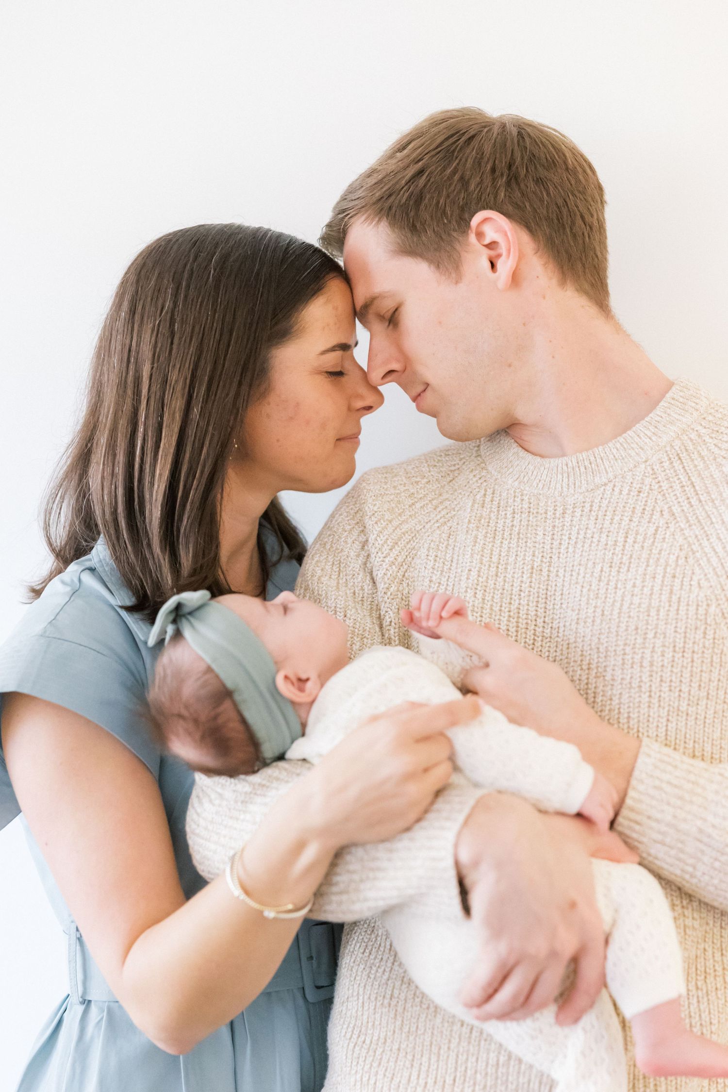 A couple sharing an intimate moment while holding their newborn baby between them.