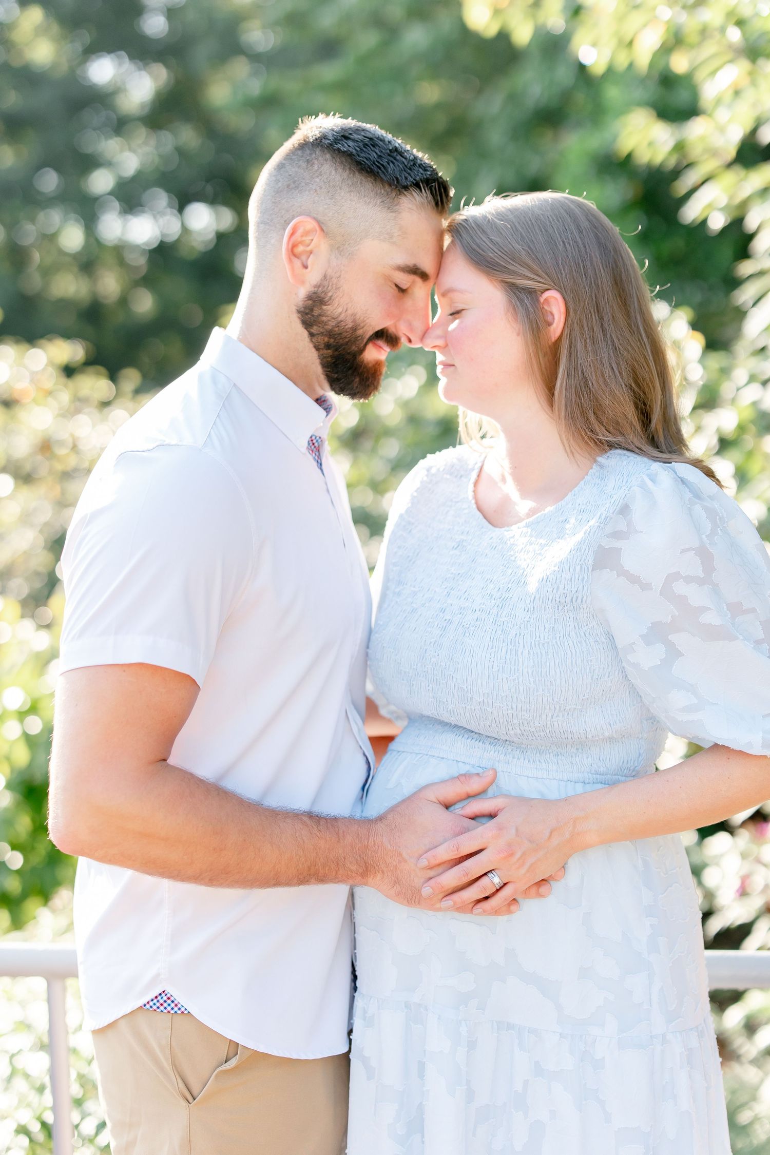 Romantic outdoor photo sequence of a couple in white clothing embracing while silhouetted against sunlit greenery.