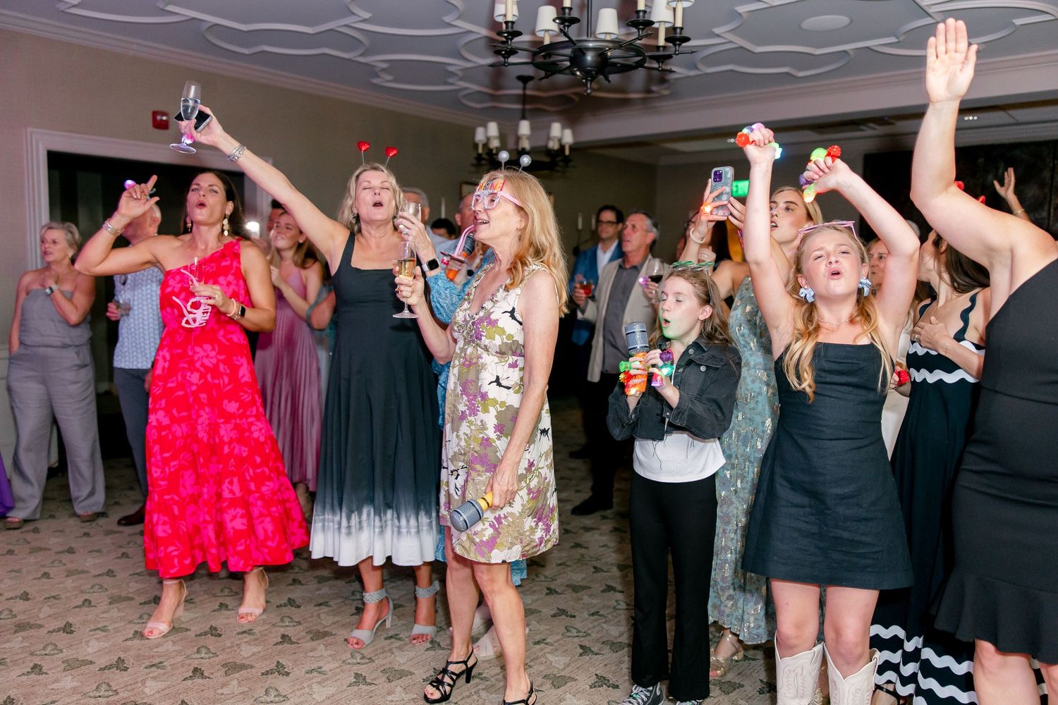 Party guests dancing and celebrating with raised arms on a lively dance floor.