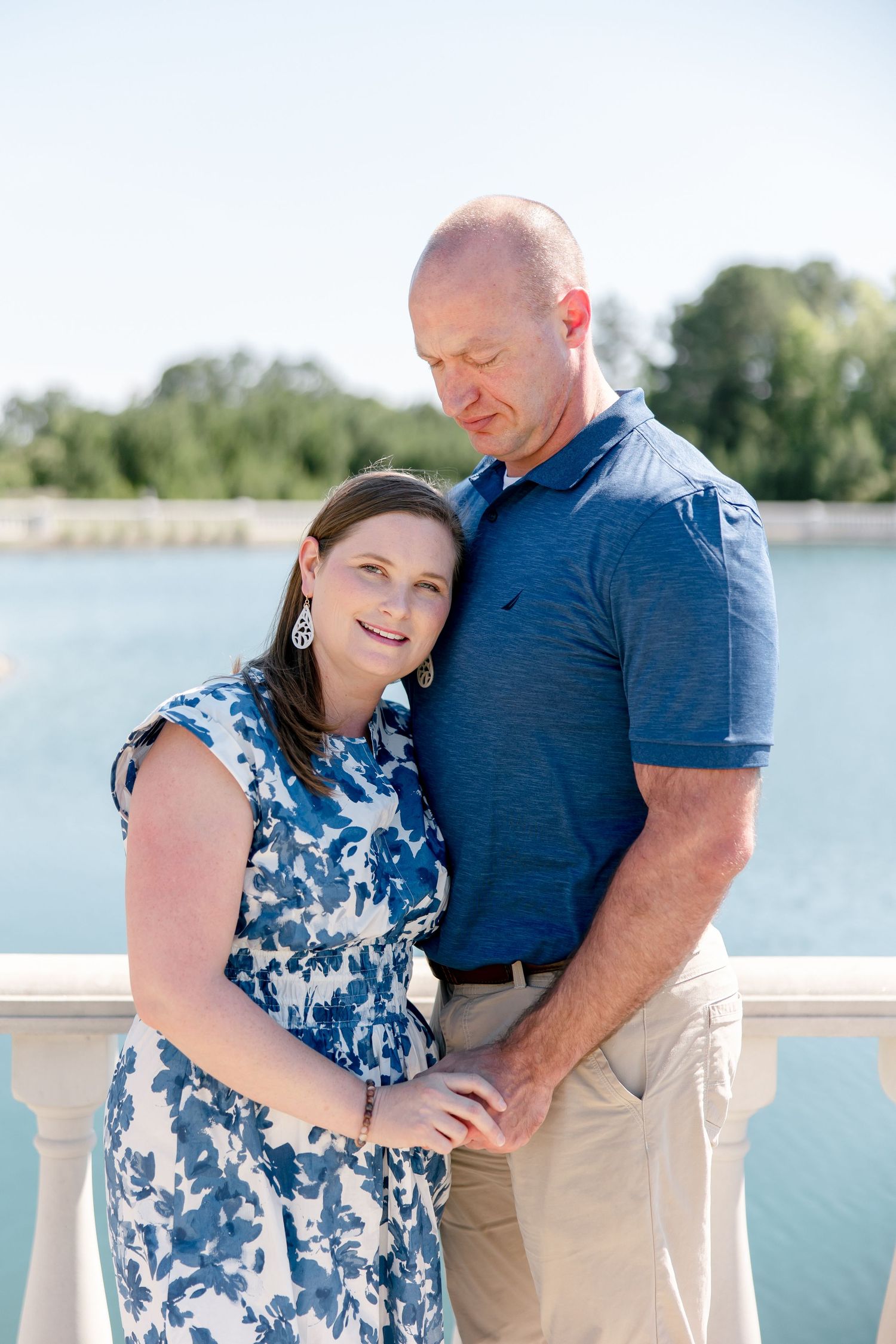 Couple in blue and navy poses affectionately by a lakeside in three successive romantic portrait shots.