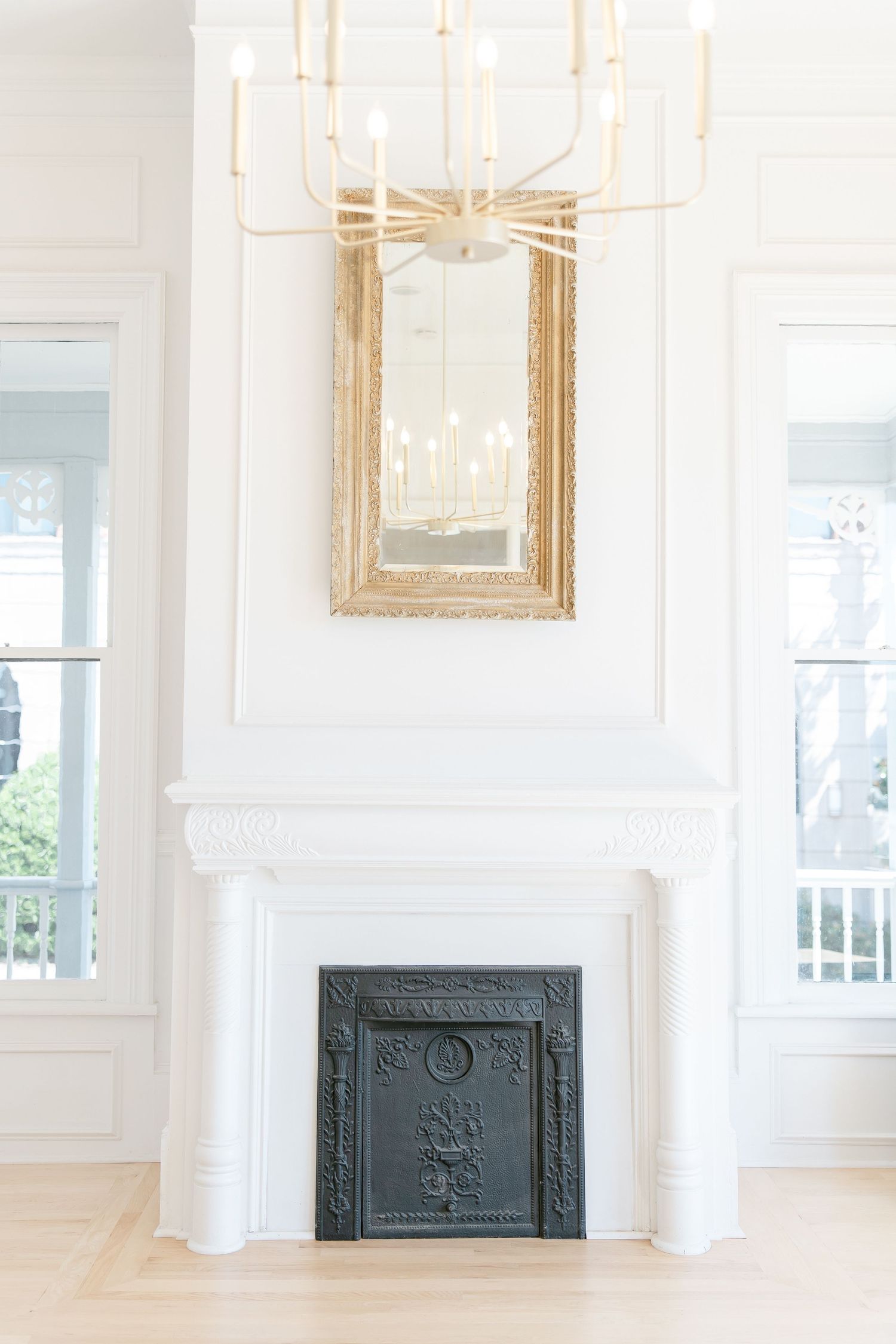 A bright, airy room with white walls, ornate gold-framed artwork, and decorative black iron radiator covers.