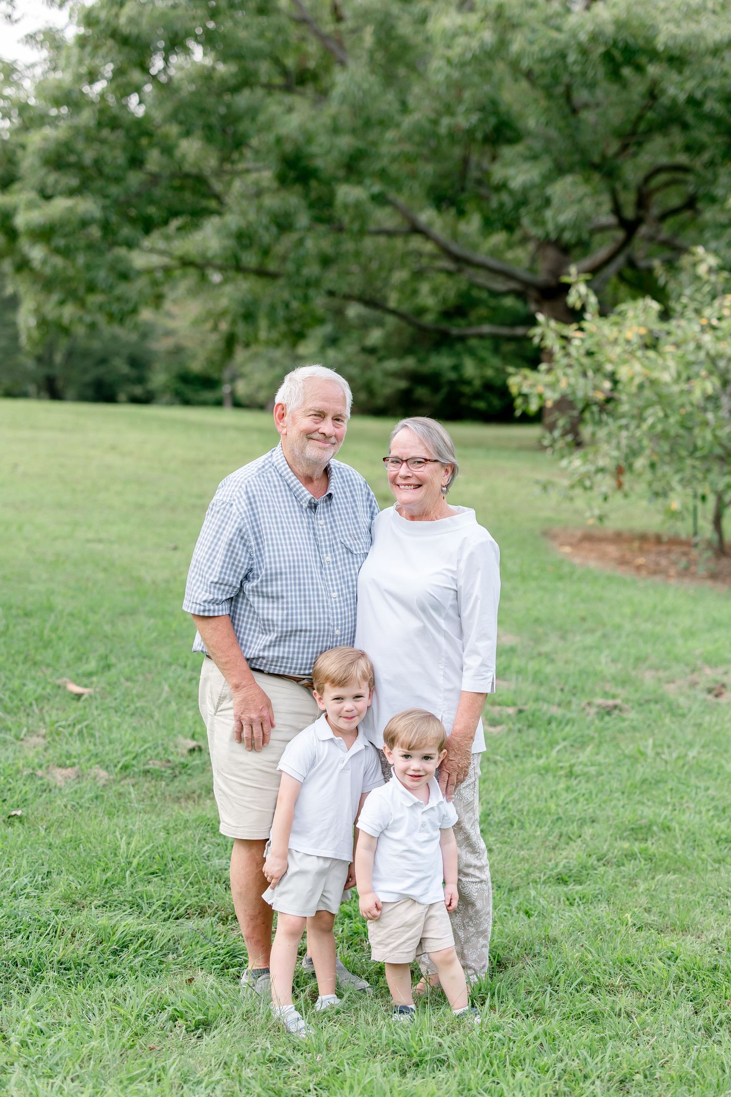 Multi-generational family portrait captured in casual attire on a grassy hillside.