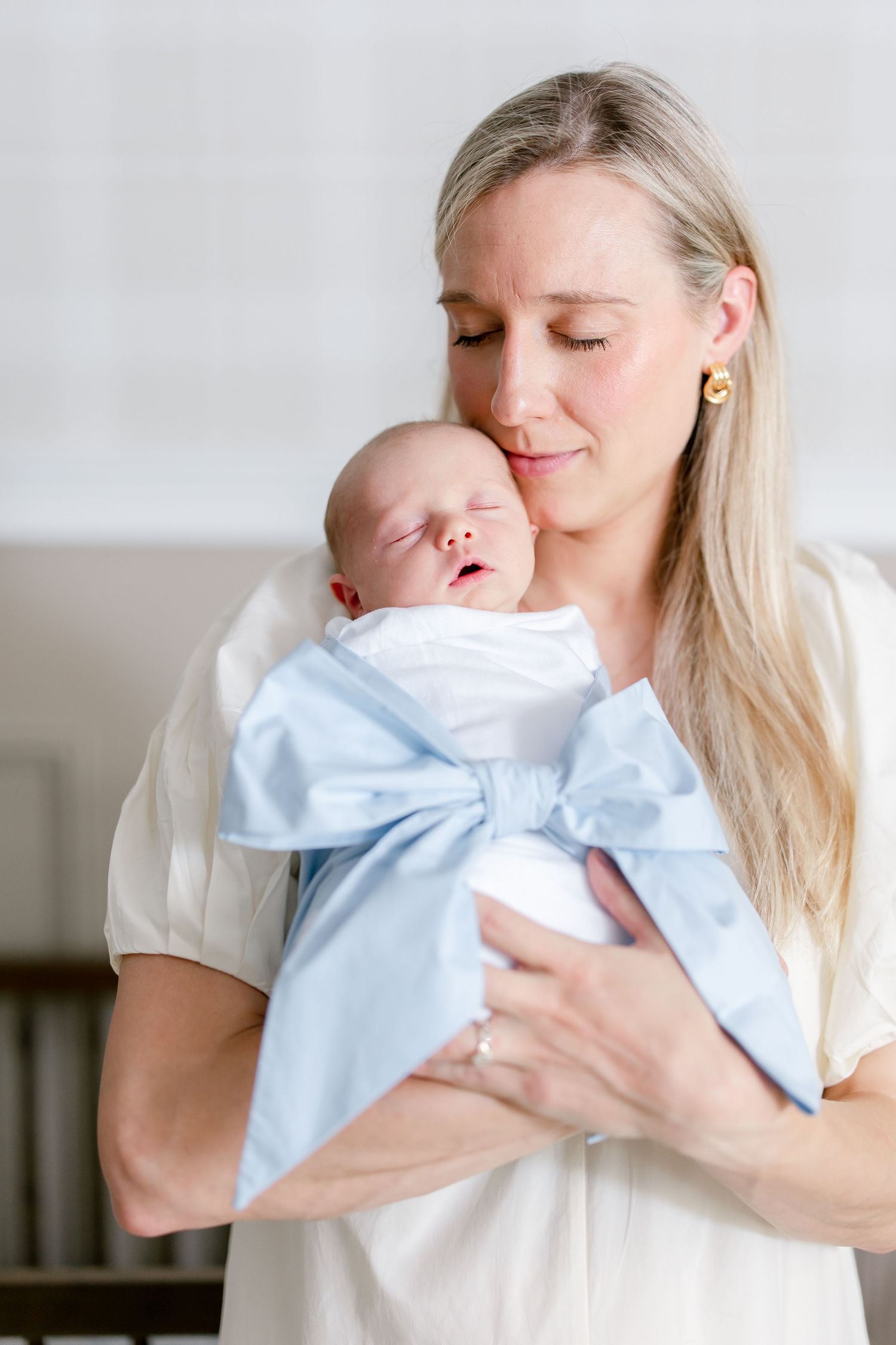 Sweet tender moments of a baby being cradled and kissed in a white room.