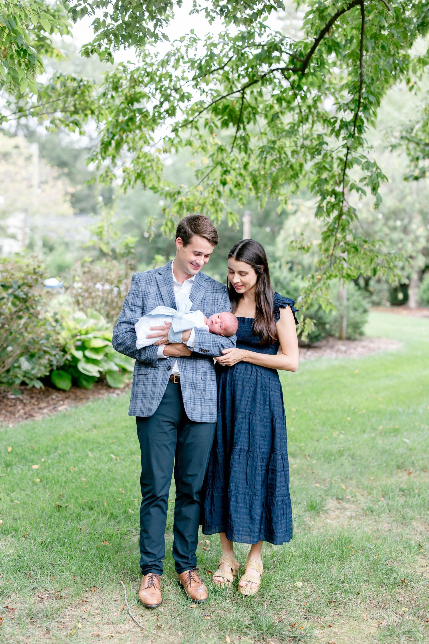 A couple sits together on grassy ground looking at something while wearing coordinating blue and gray outfits.