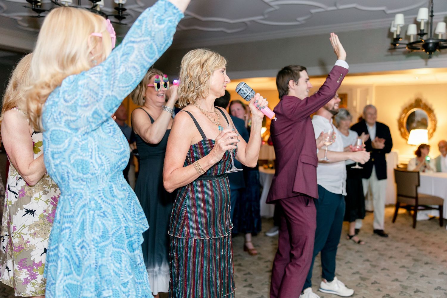 People dancing and celebrating at an indoor event with blue and white decorative elements.